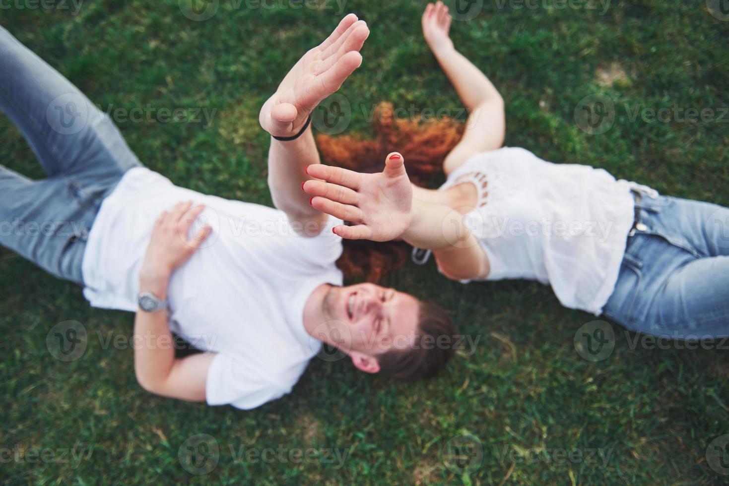 alegre pareja tendida en la hierba. jóvenes al aire libre. felicidad y armonía. foto