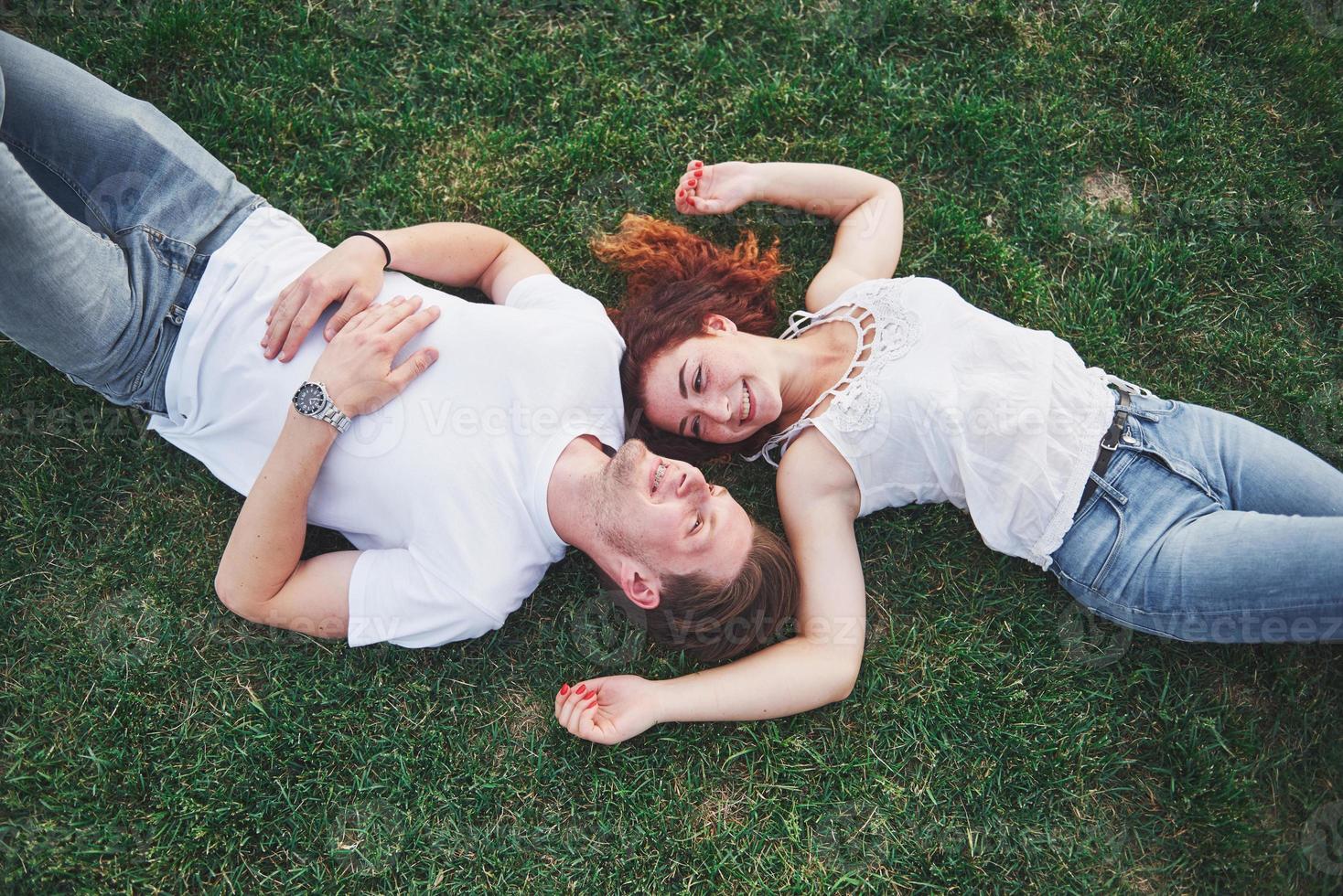 una pareja romántica de jóvenes tumbados en el césped del parque. vista superior foto