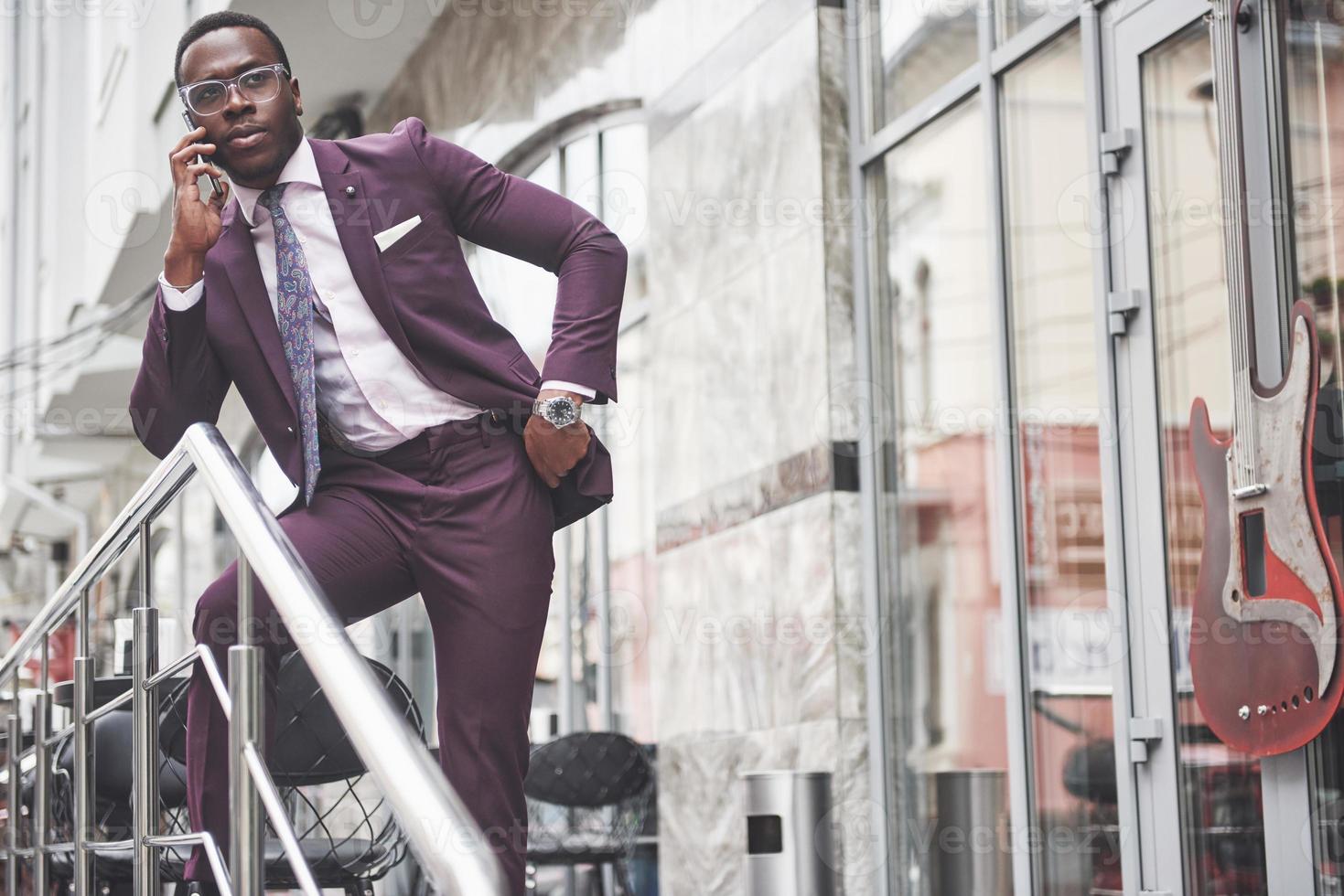 Retrato de un joven y guapo empresario afroamericano hablando en un traje por teléfono. preparándose para una reunión de negocios. foto