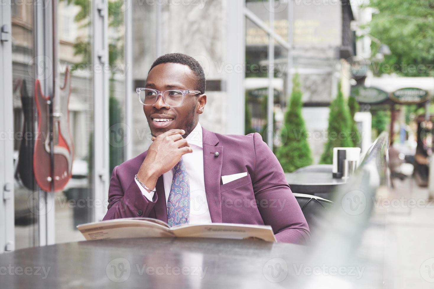 A beautiful African American businessman reads a menu in a cafe photo