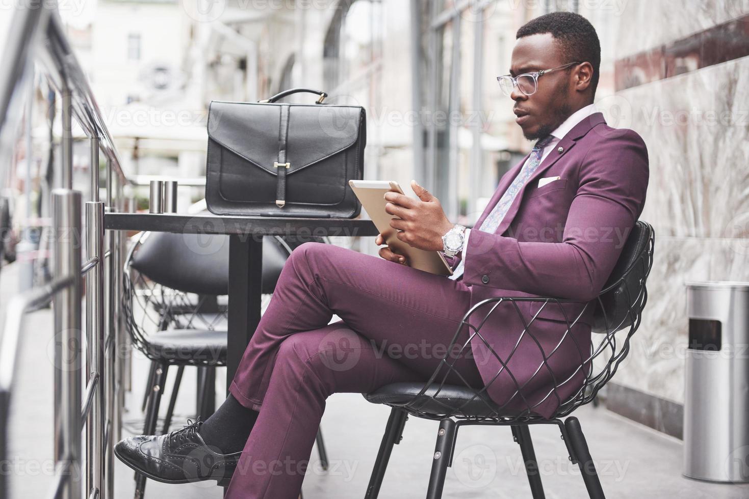 A beautiful African American businessman reads a menu in a cafe photo