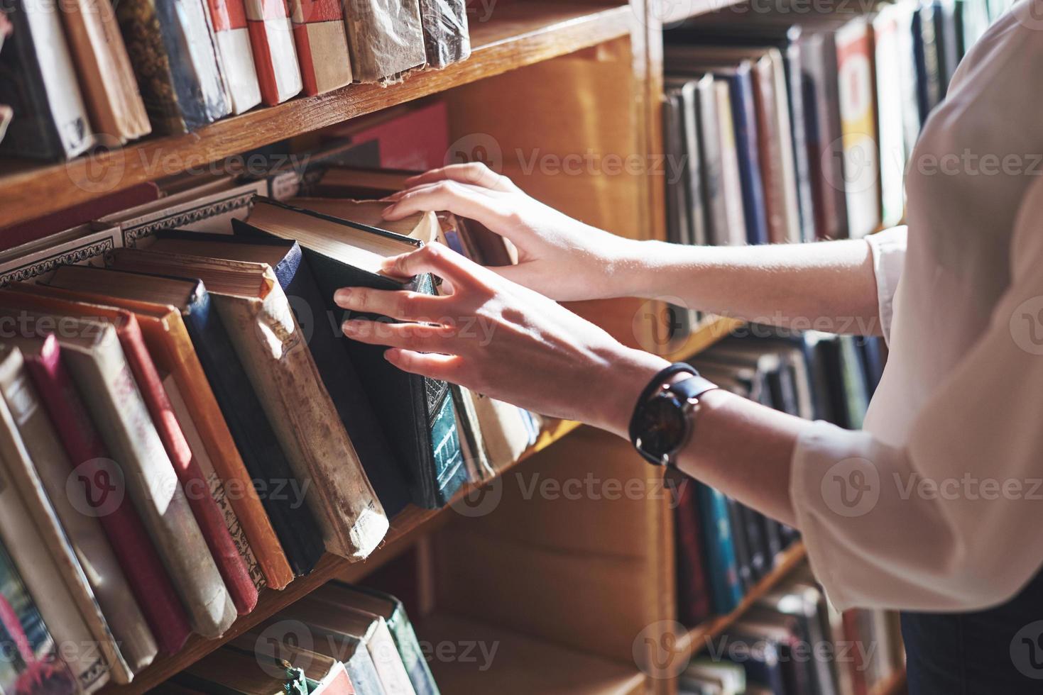 A young girl student looking for literature near the bookshelves in the old library photo