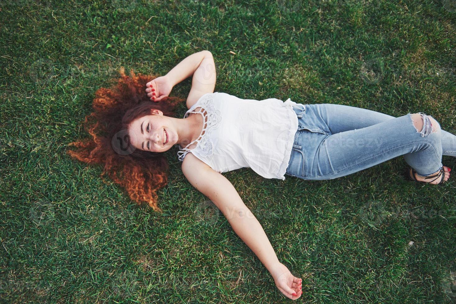 Relaxing girl with red, lying on the grass. Woman relaxes outdoors. photo