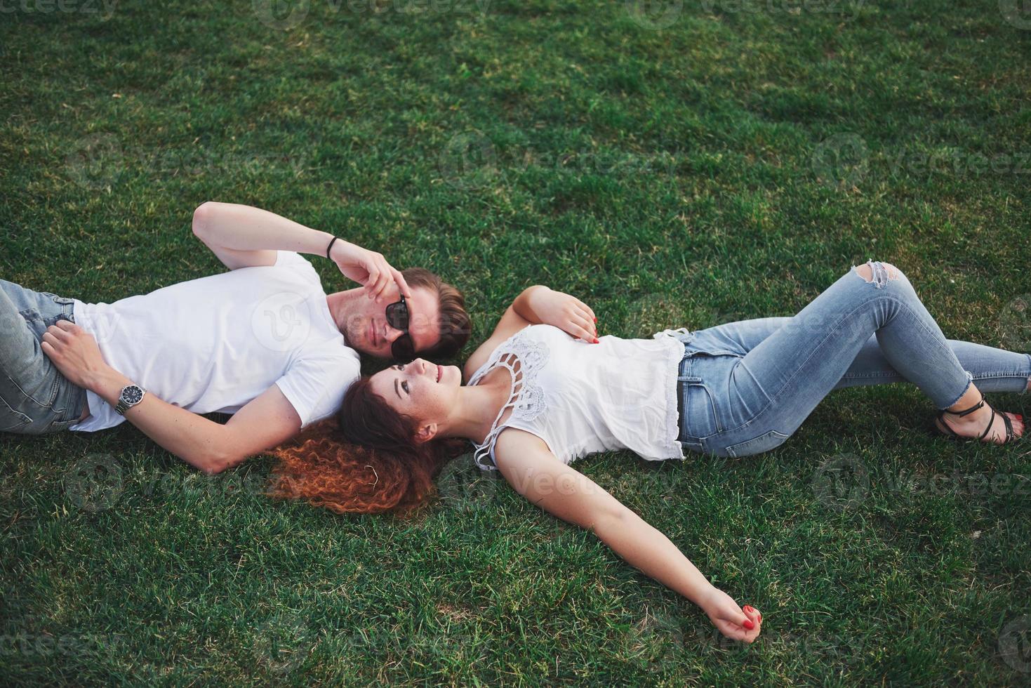 alegre pareja tendida en la hierba. jóvenes al aire libre. felicidad y armonía. foto