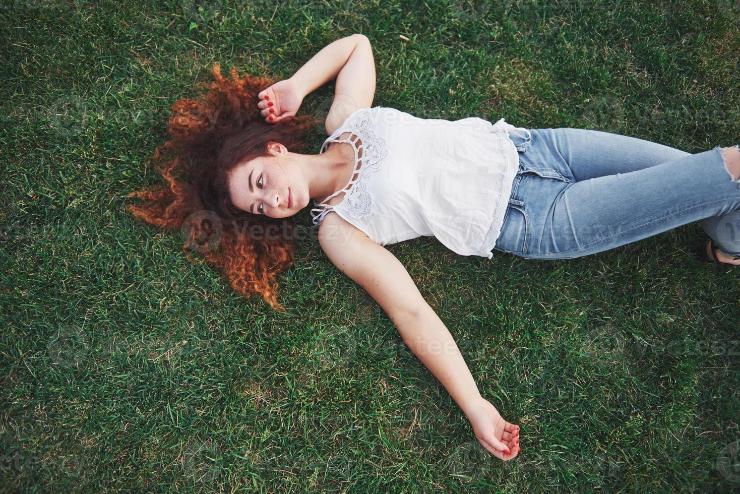 Relaxing girl with red, lying on the grass. Woman relaxes outdoors. photo