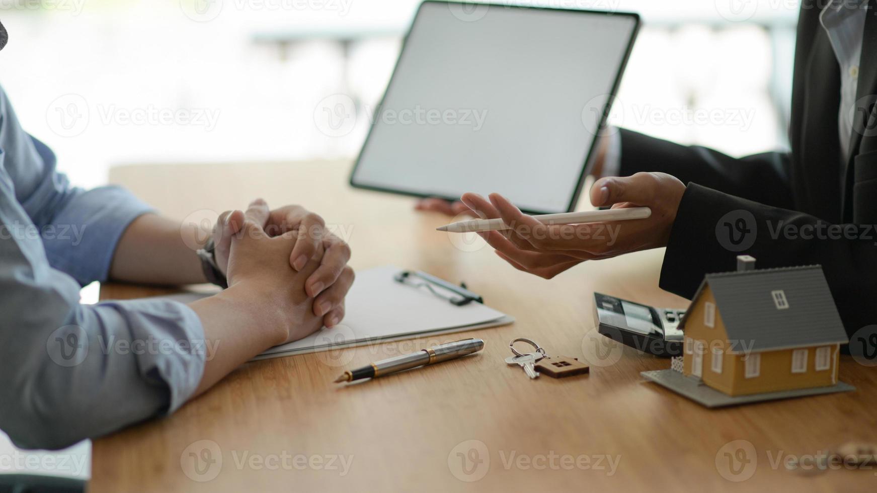 Insurance agents with tablet are introducing real estate insurance programs for customer. photo