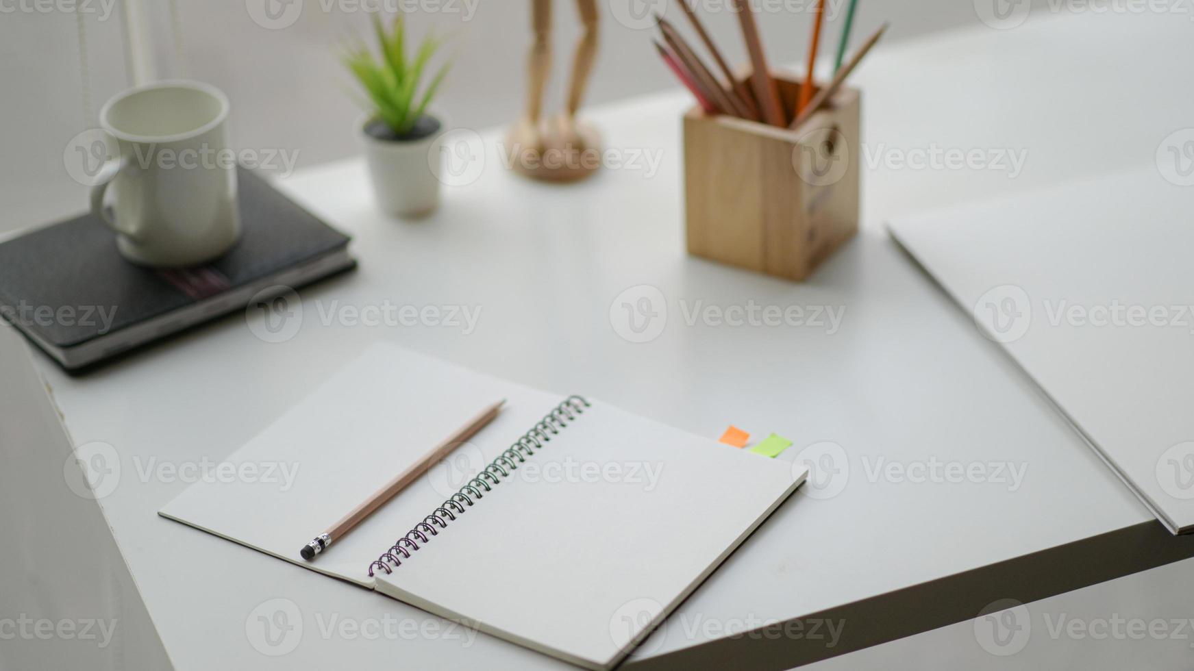 Open the notebook on the desk in a simple workspace complete with stationery and coffee. photo