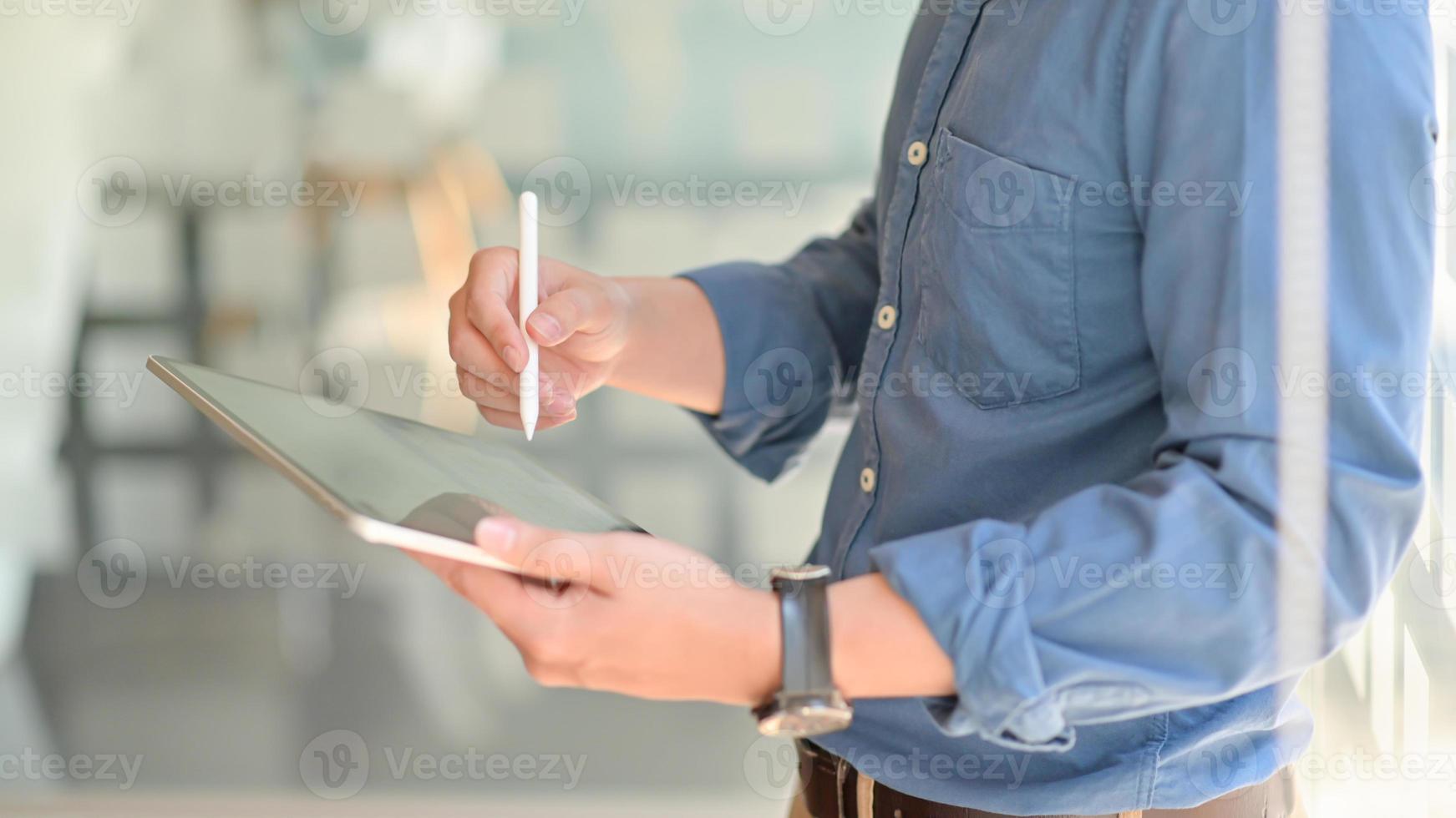 dos jóvenes empresarios consultaron sobre su trabajo usando una tableta mientras estaban parados en el lugar de trabajo, imagen de vista lateral. foto