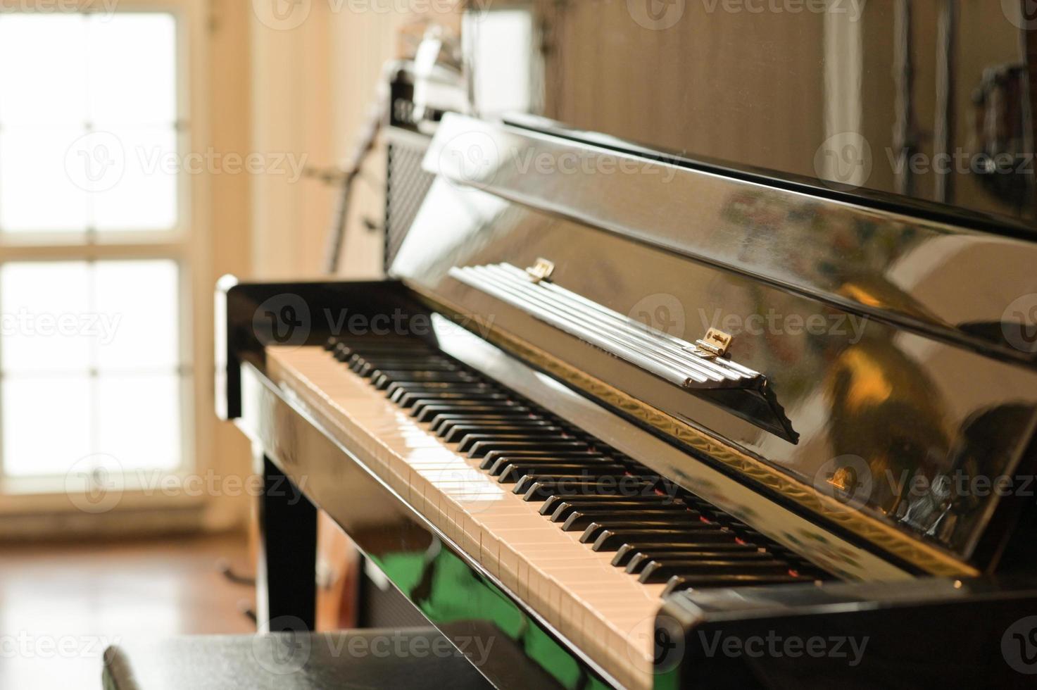Toma recortada de piano clásico en una habitación con luz natural a través de una hermosa ventana. foto