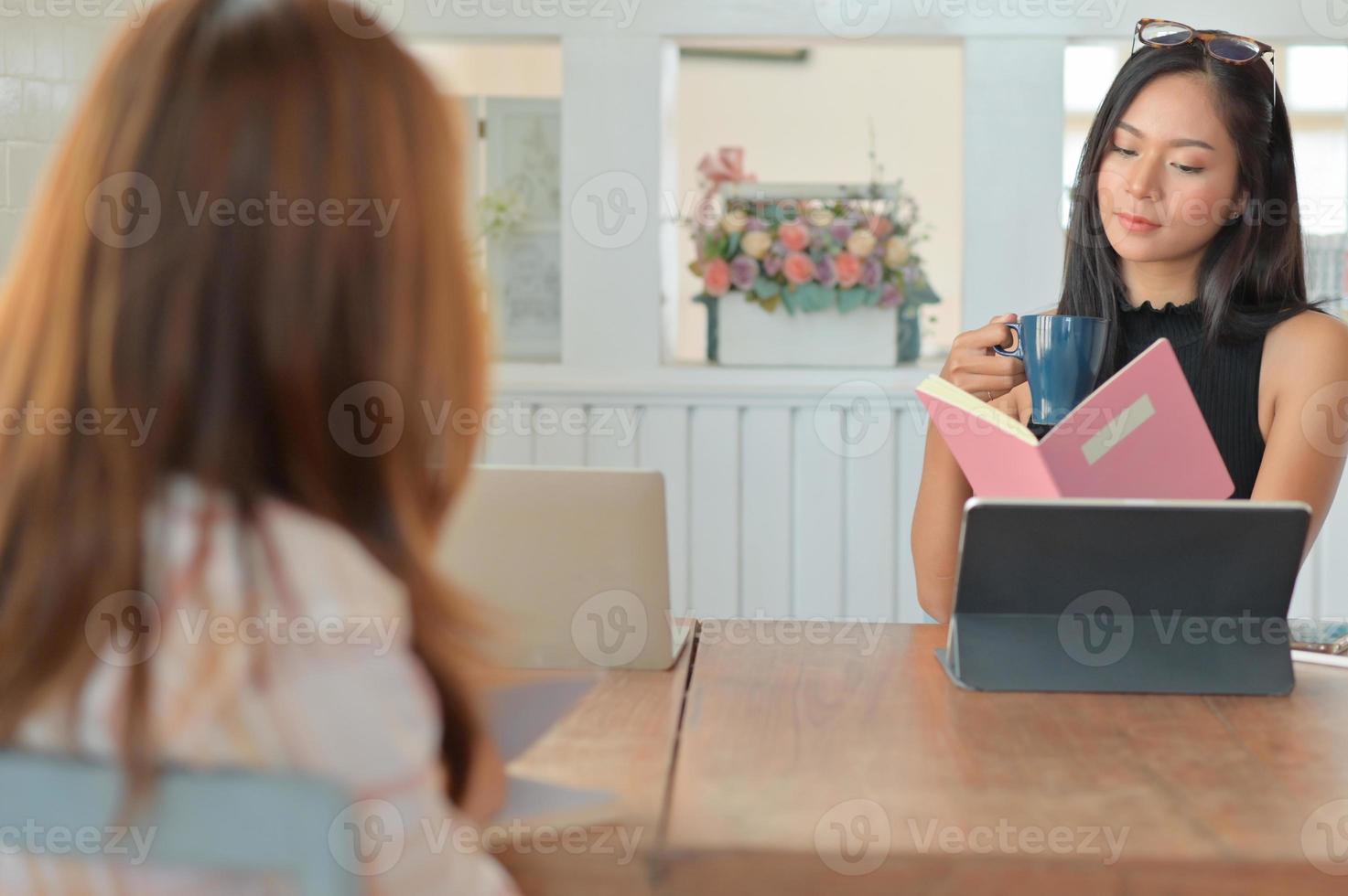 empresaria sosteniendo una taza de café y un archivo en su mano. Ella está revisando su currículum para las solicitudes de empleo. foto