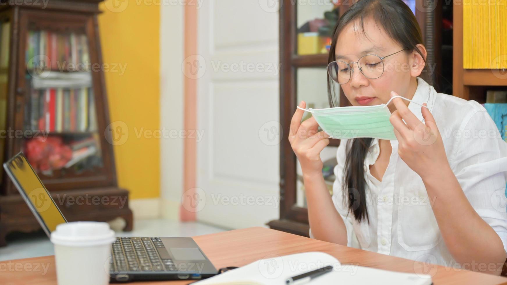 Asian woman is wearing a mask. She works at home to protect against Corona virus or Covid-19. photo