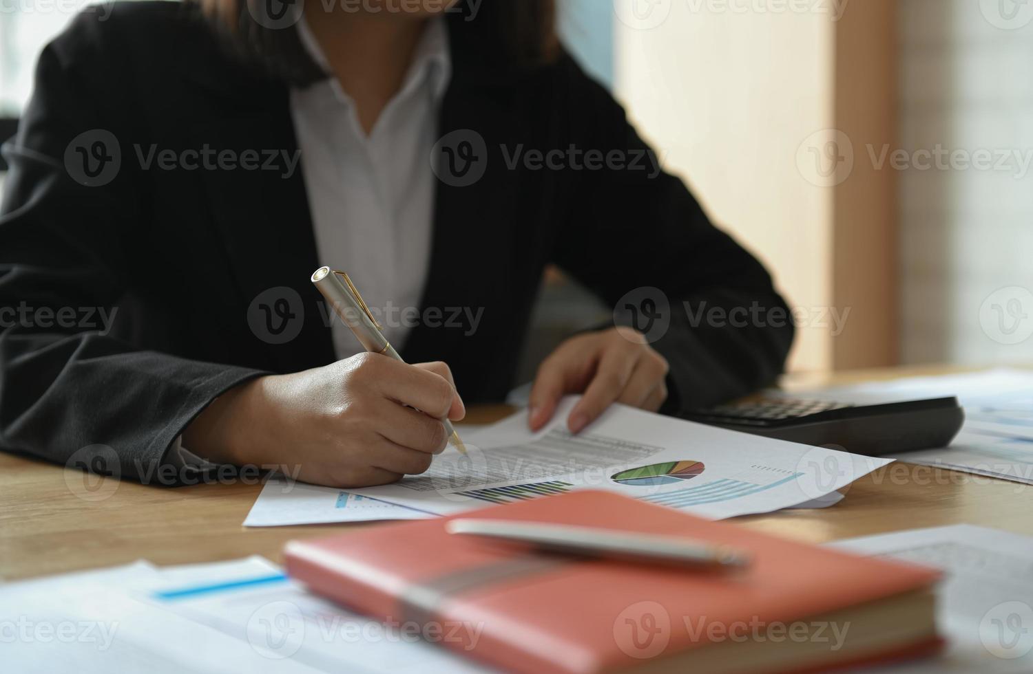 Businesswomen are working on the table in the office. She pointed the graph to analyze. photo