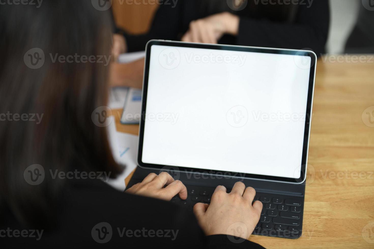 Cropped shot of a female employee typing a keyboard on a laptop with a blank white screen. photo