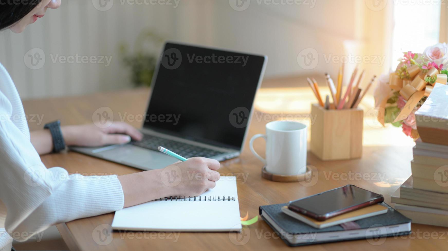 Young businesswomen are taking notes and using a blank screen laptop in a modern office. photo