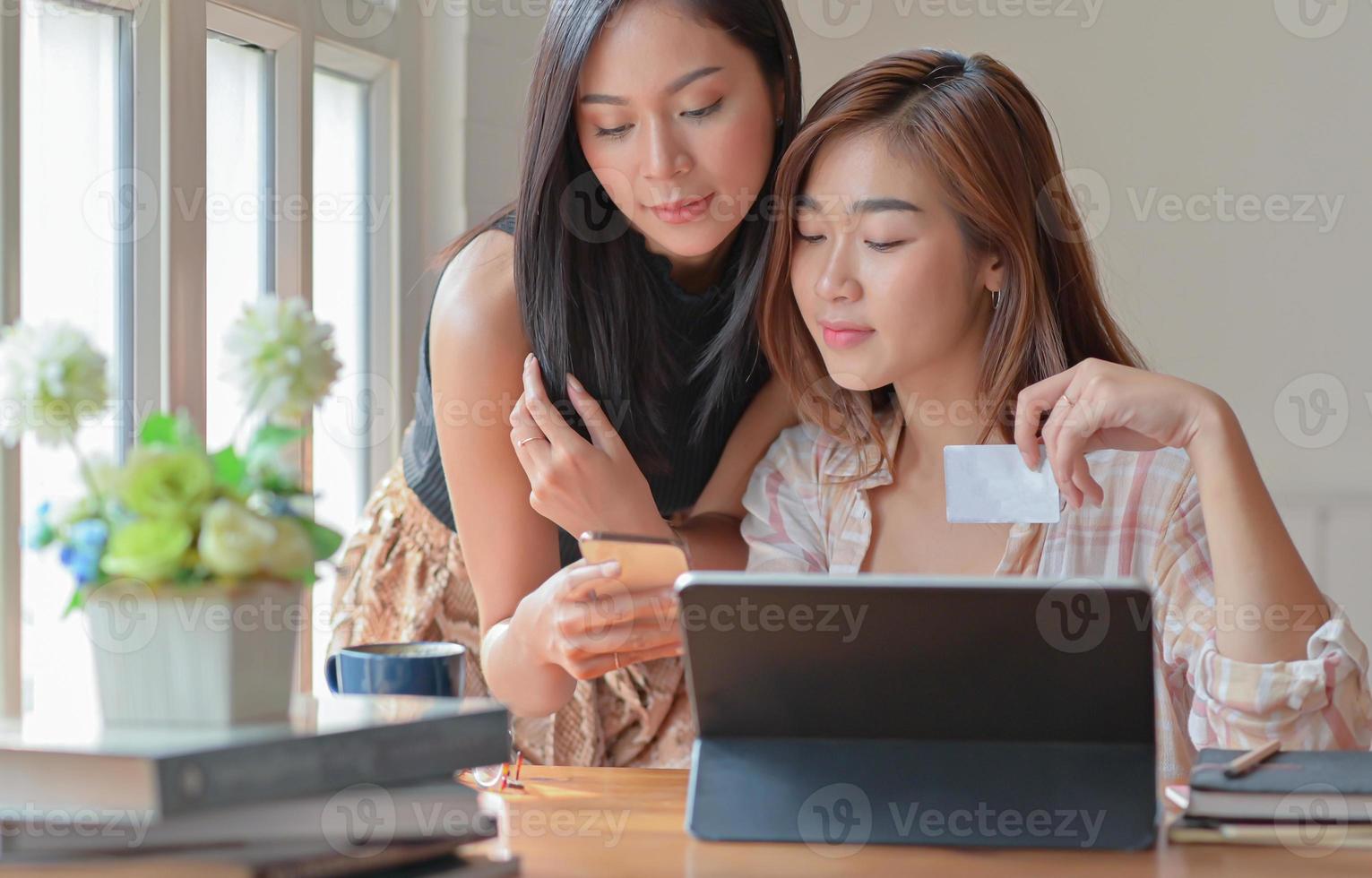 Two teenage girls are shopping online with a tablet at home to order and pay online by credit card. photo