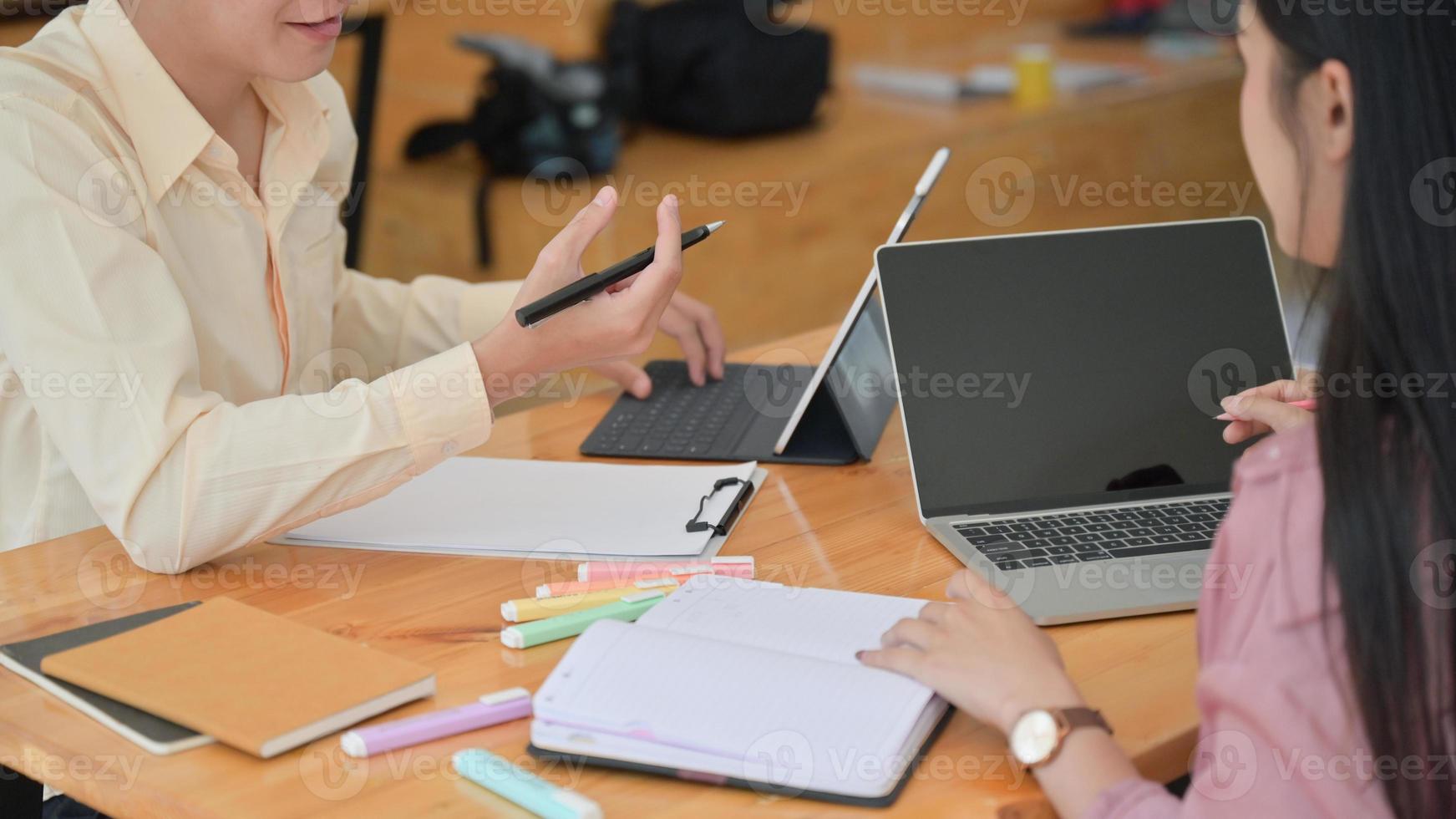 Two male and female professionals are planning to present a new project in the future. With a laptop and desk accessories. photo