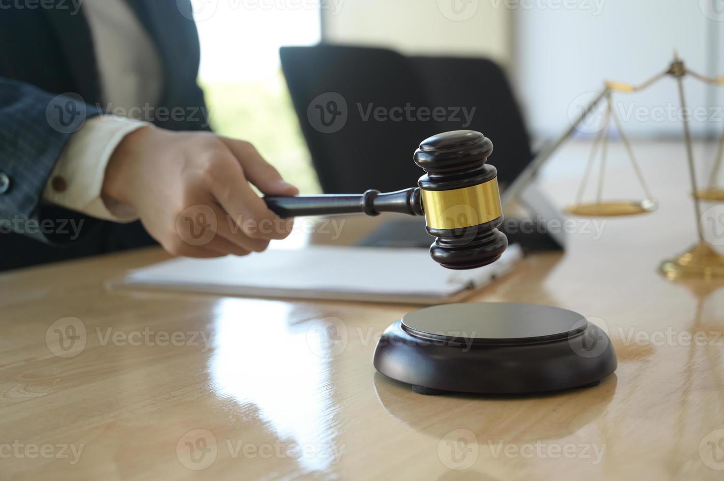 Concept of justice, Lawyer holding a hammer pretending to hit on a wooden tray put on the desk. photo