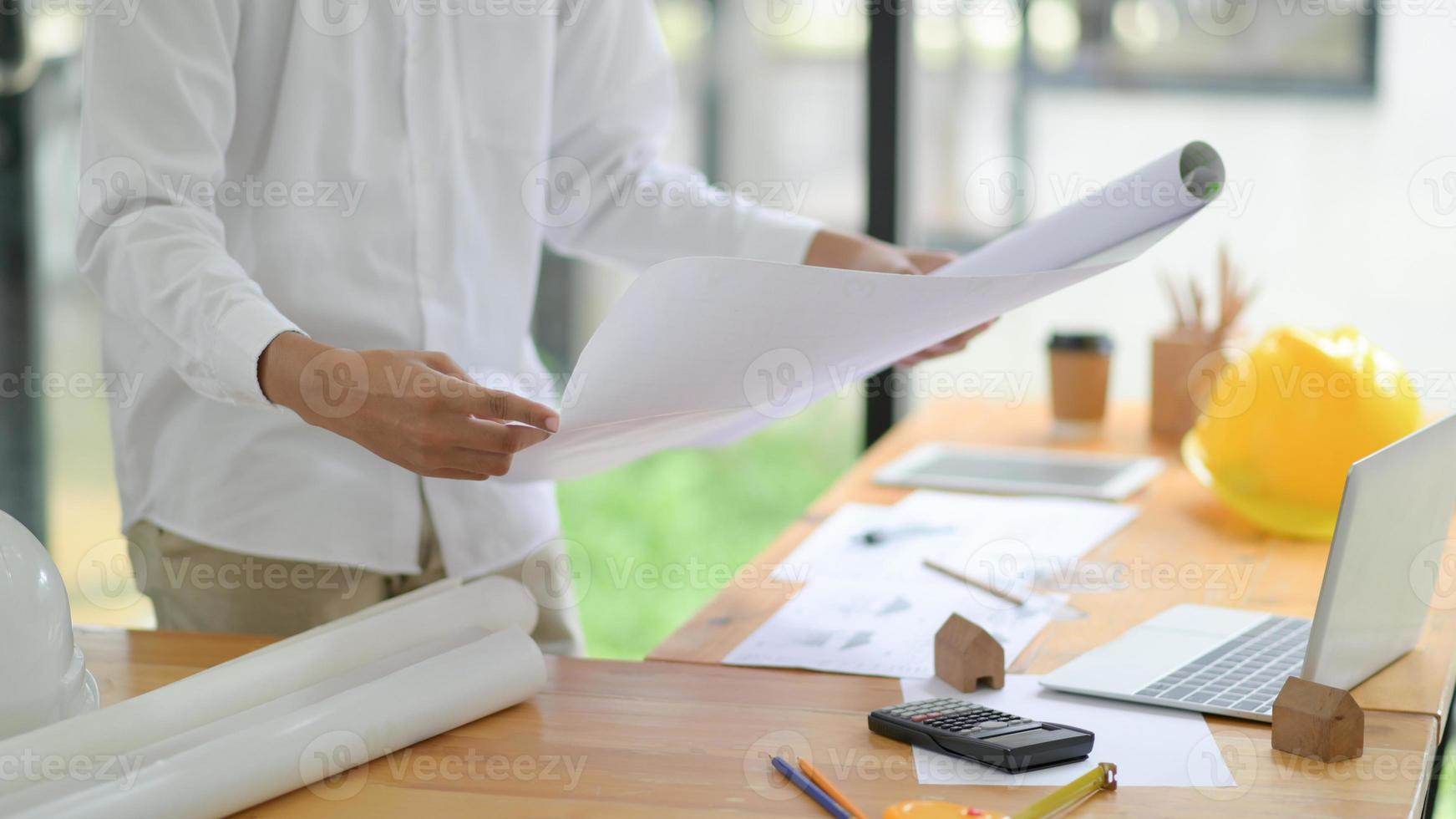 The architect is designing the construction. He drafts the floor plan to present to the client. photo