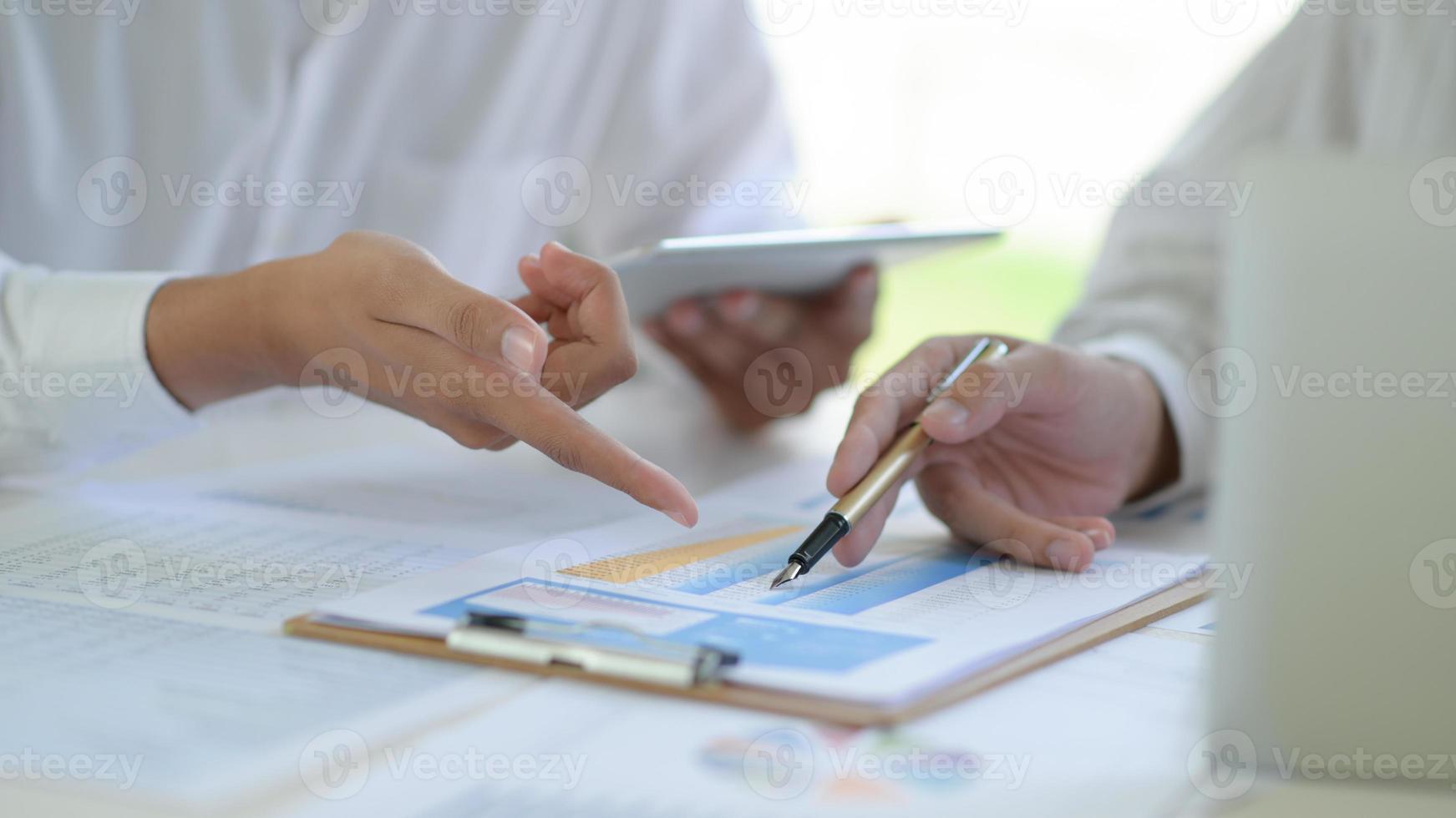 Two business teams discuss and analyze the graphs of project working together in office. photo