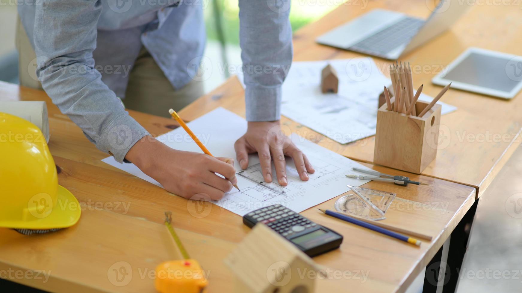 The architect is designing the construction. He drafts the floor plan to present to the client. photo