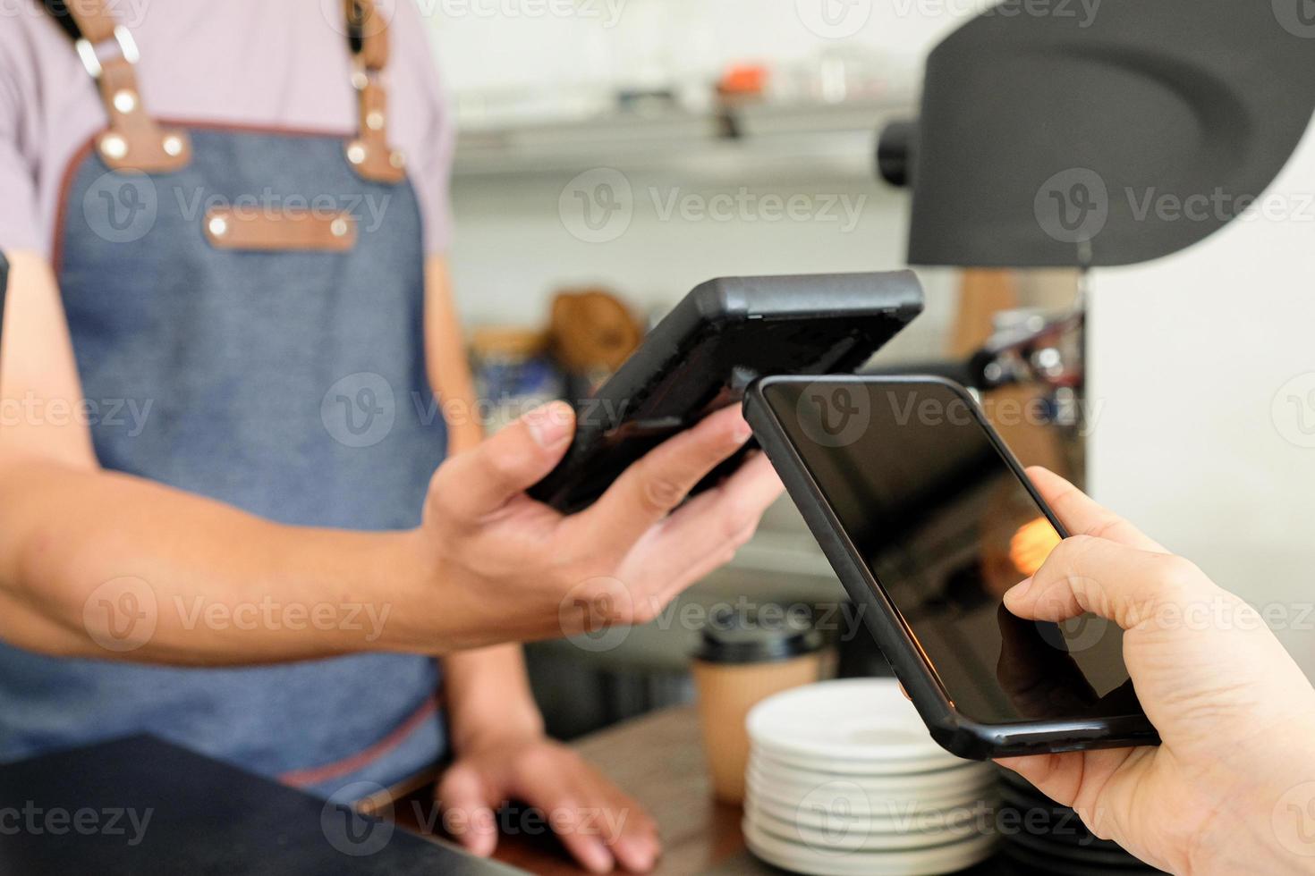 Customer and sale people are holding a smartphone to pay via the App. photo