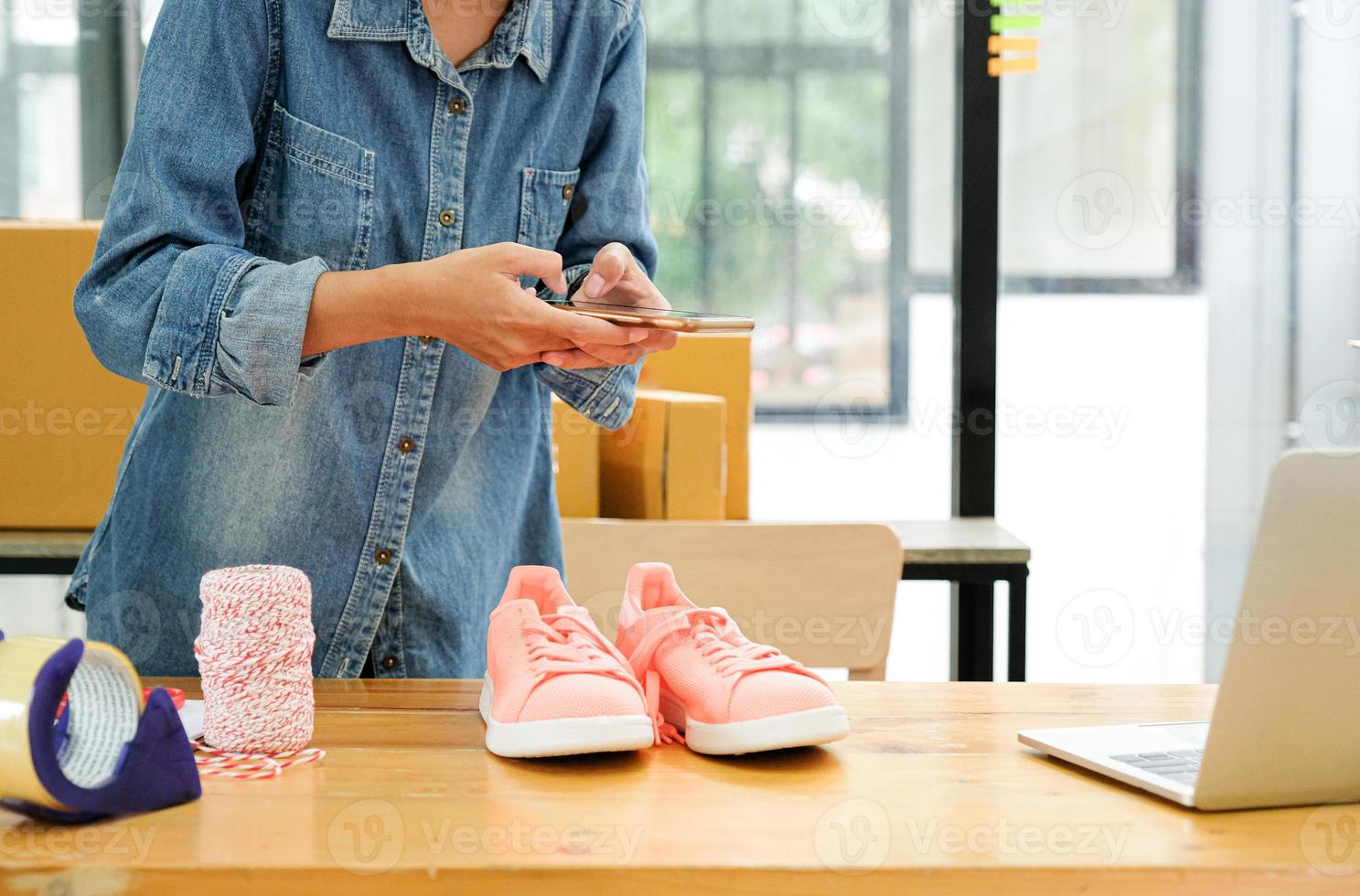 Online sellers use mobile phone to take pictures of shoes sent to customers. photo