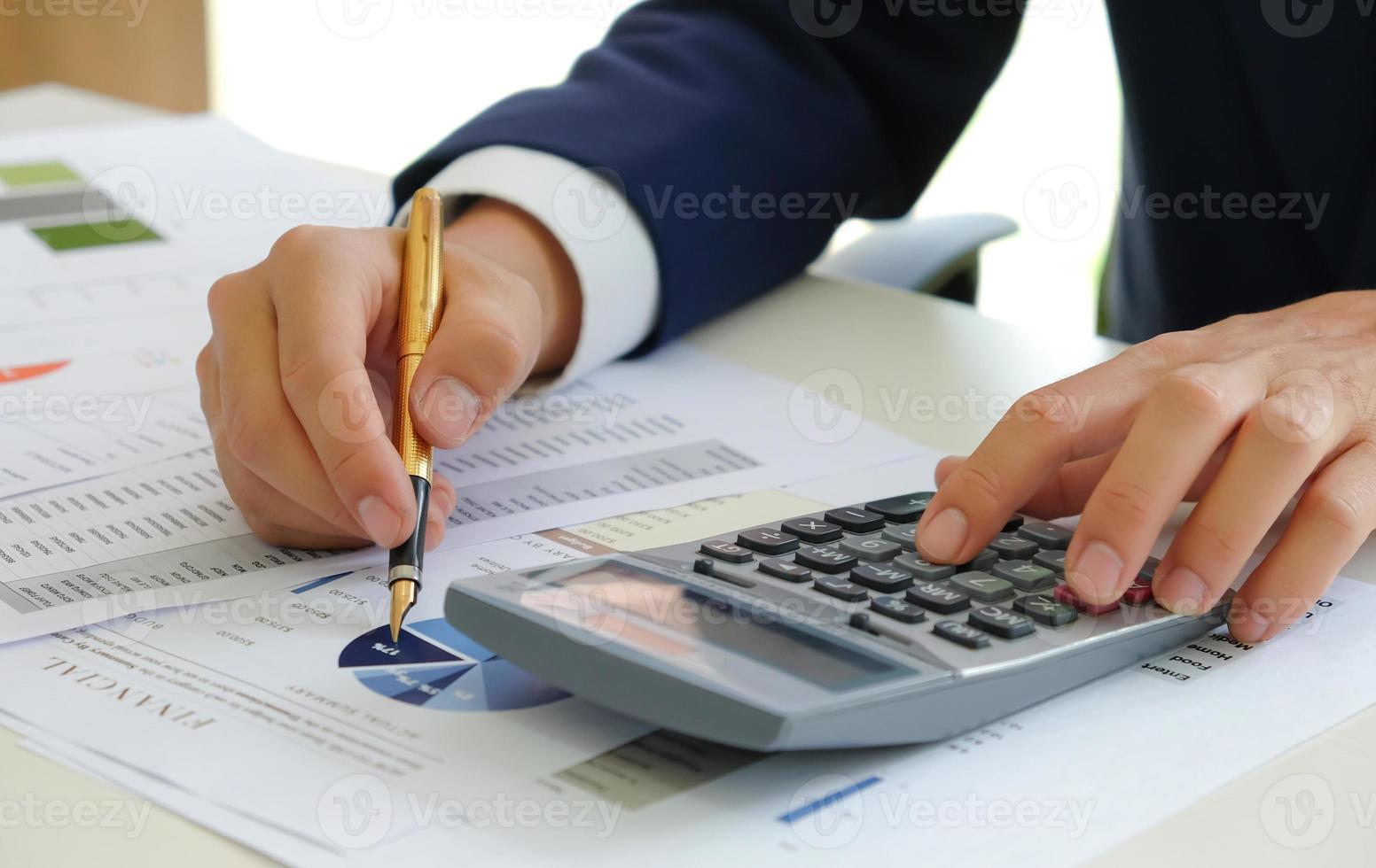 Cropped shot of Analysts use calculators and pointers on graphs to assess the fluctuating stock market situation. photo