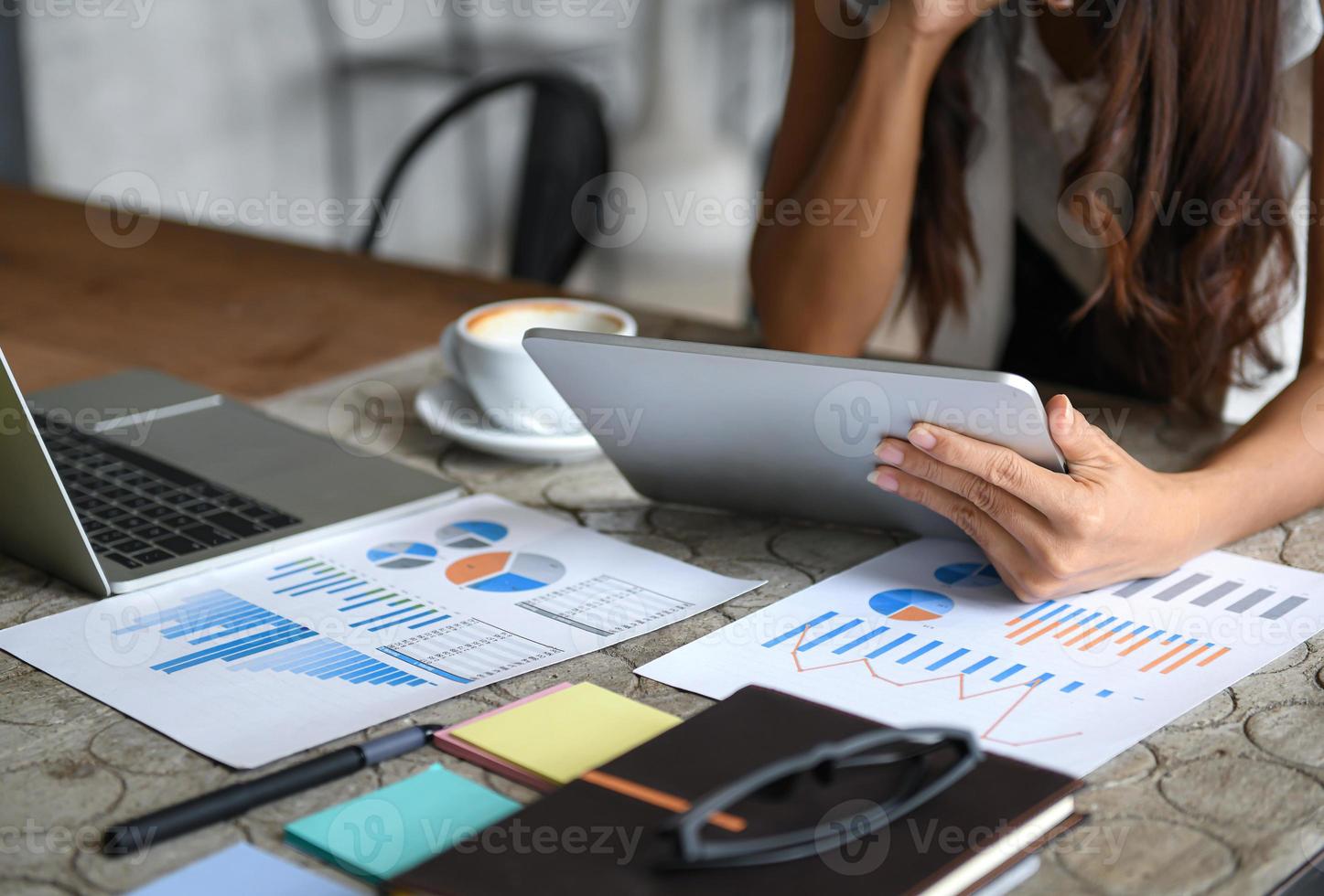 Female businessmen are using the tablet during leisure. Graphs, documents placed on the table. photo