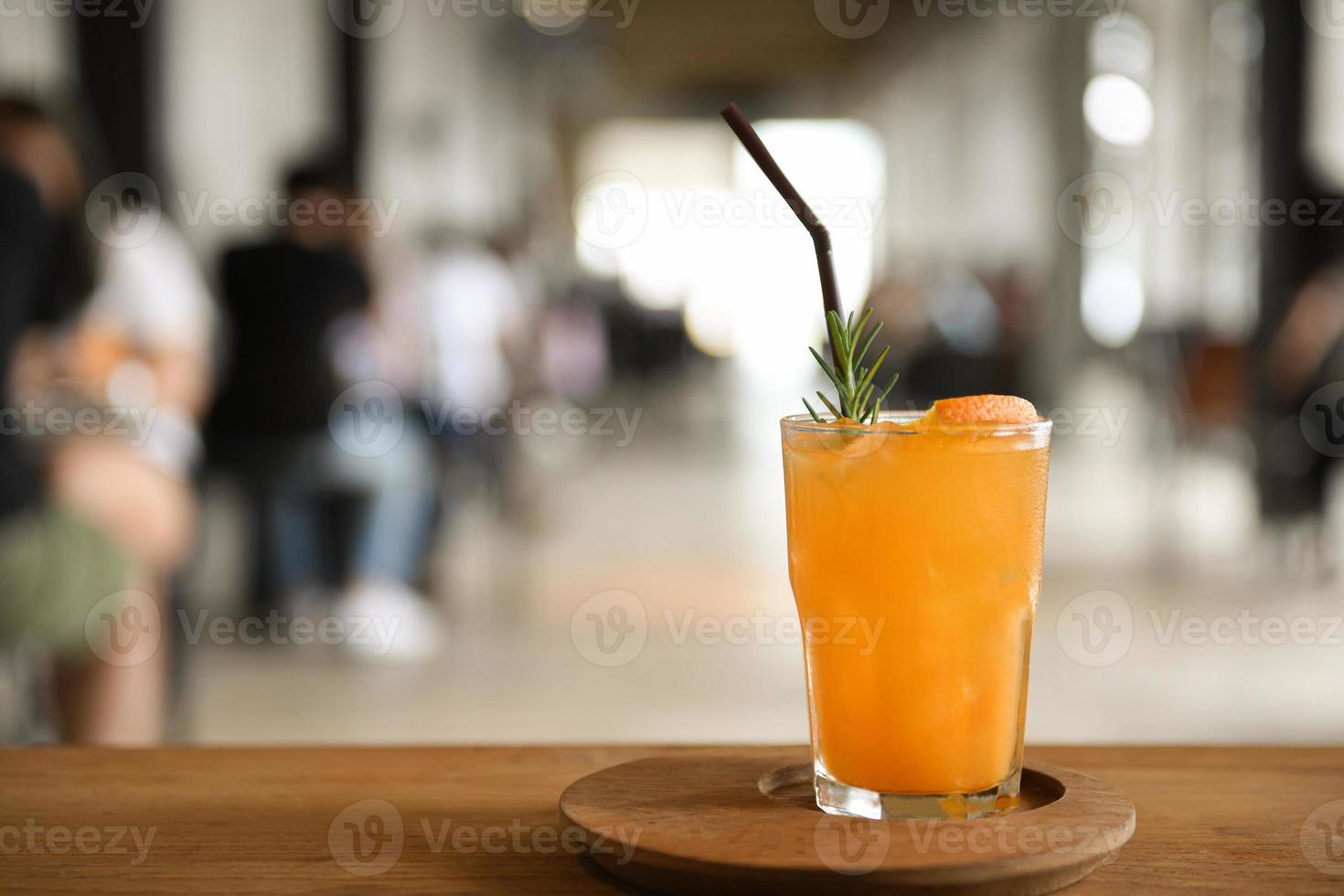 vaso de jugo de naranja en una bandeja de madera colocada sobre una mesa en el café fondo borroso. foto