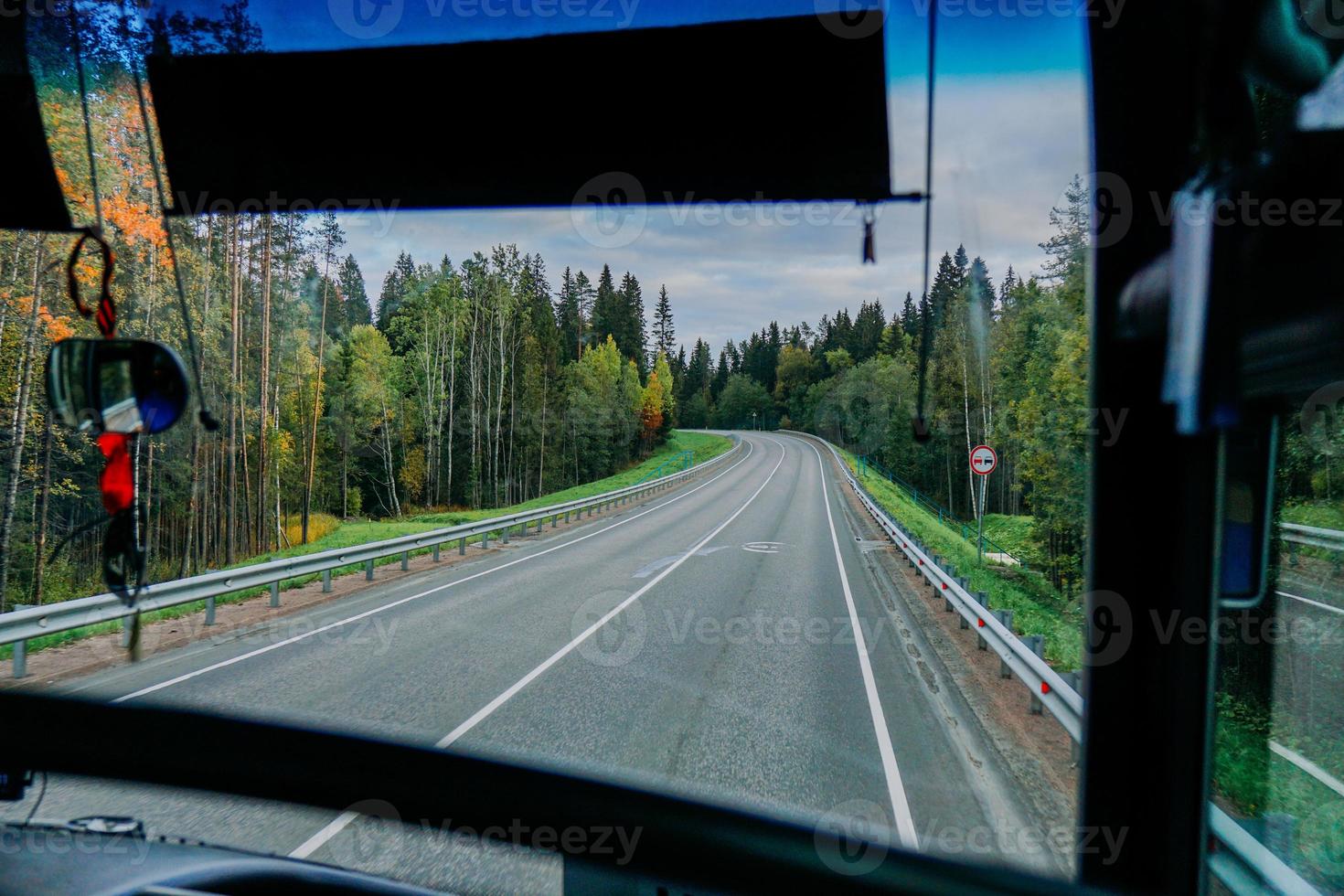 View of the road and the autumn forest through the bus window. Road trip photo