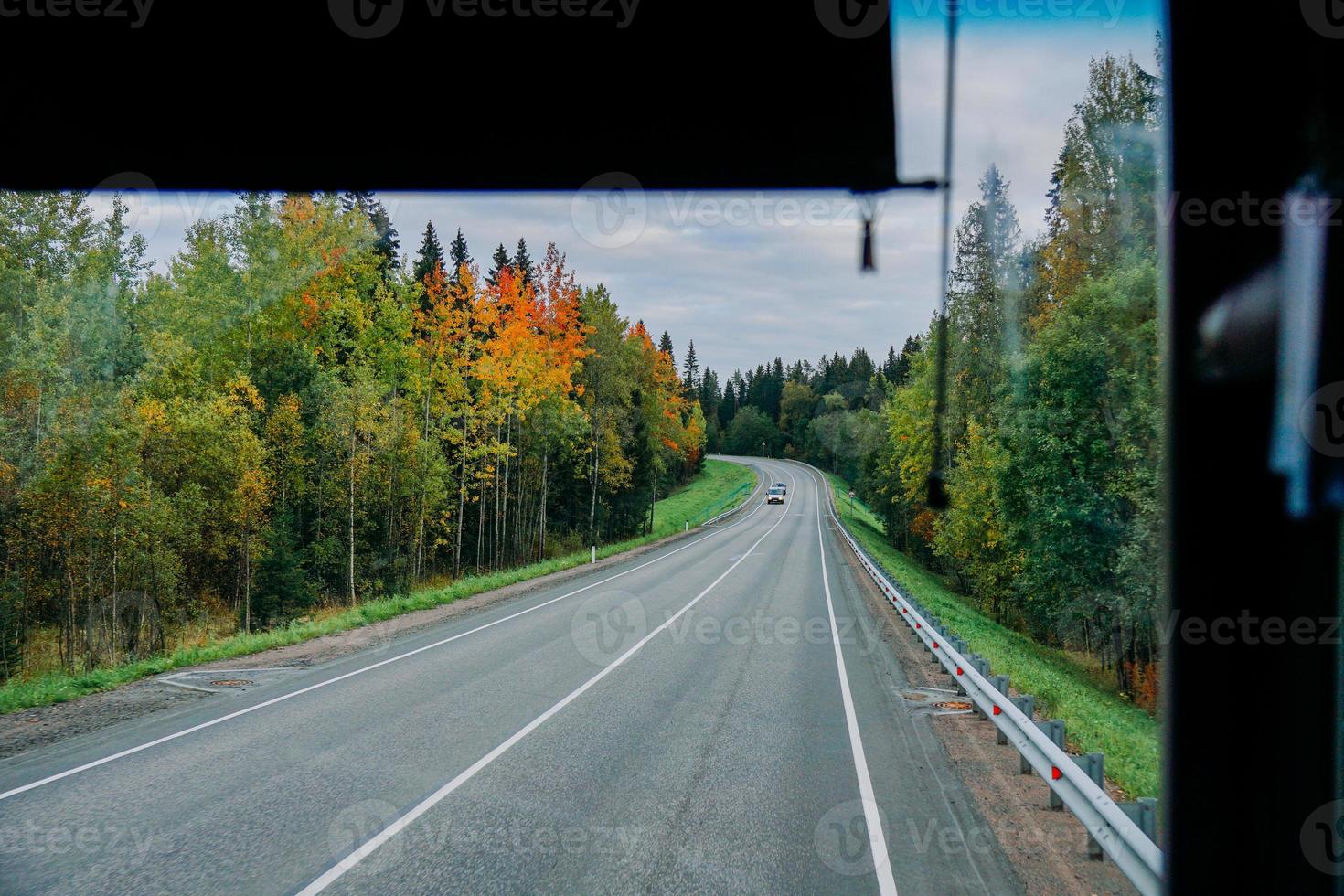 vista de la carretera y el bosque otoñal a través de la ventana del autobús. viaje foto