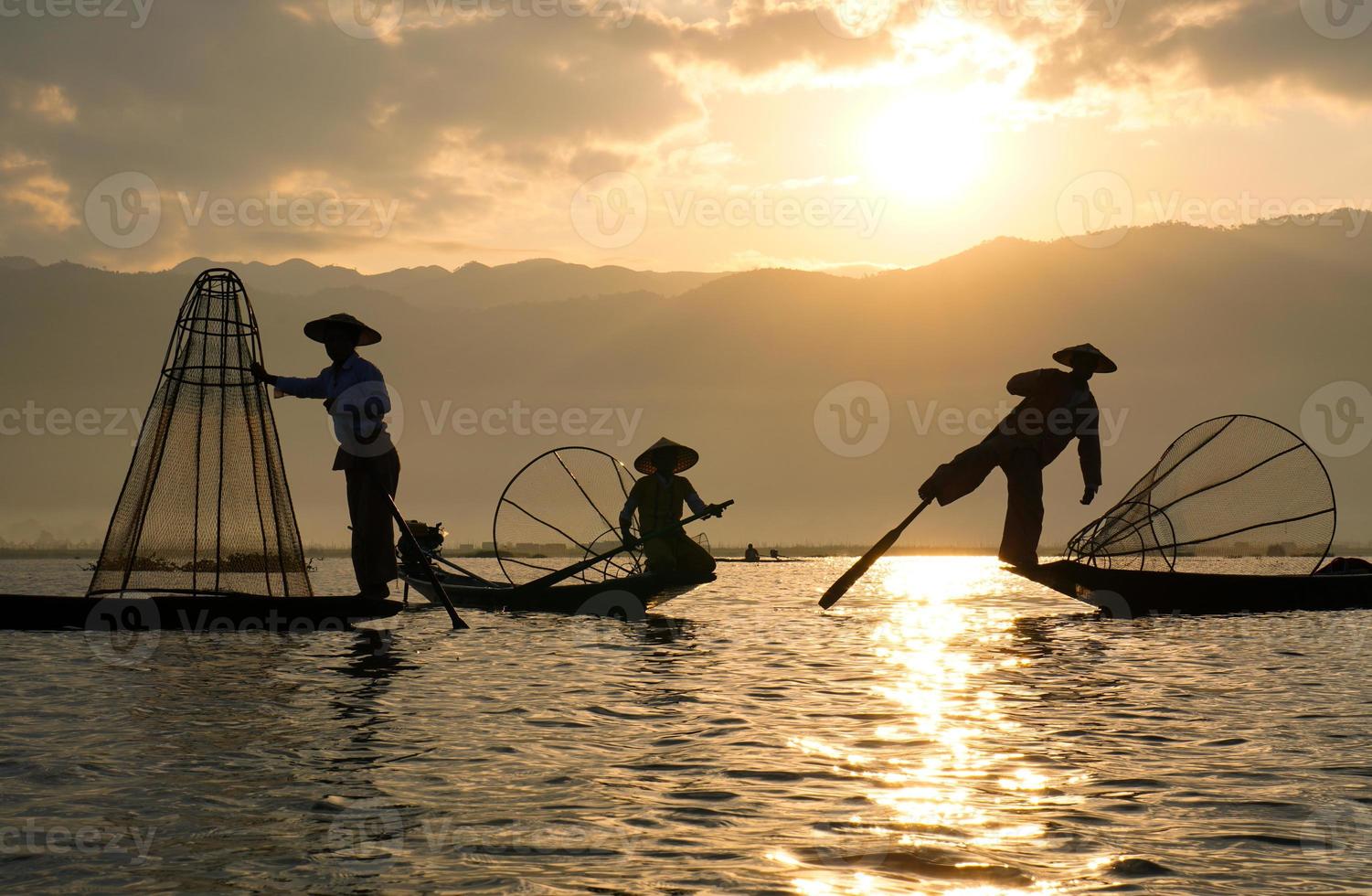 Familia de pescadores asiáticos locales, incluidos padre e hijos en barco en el lago Inle foto