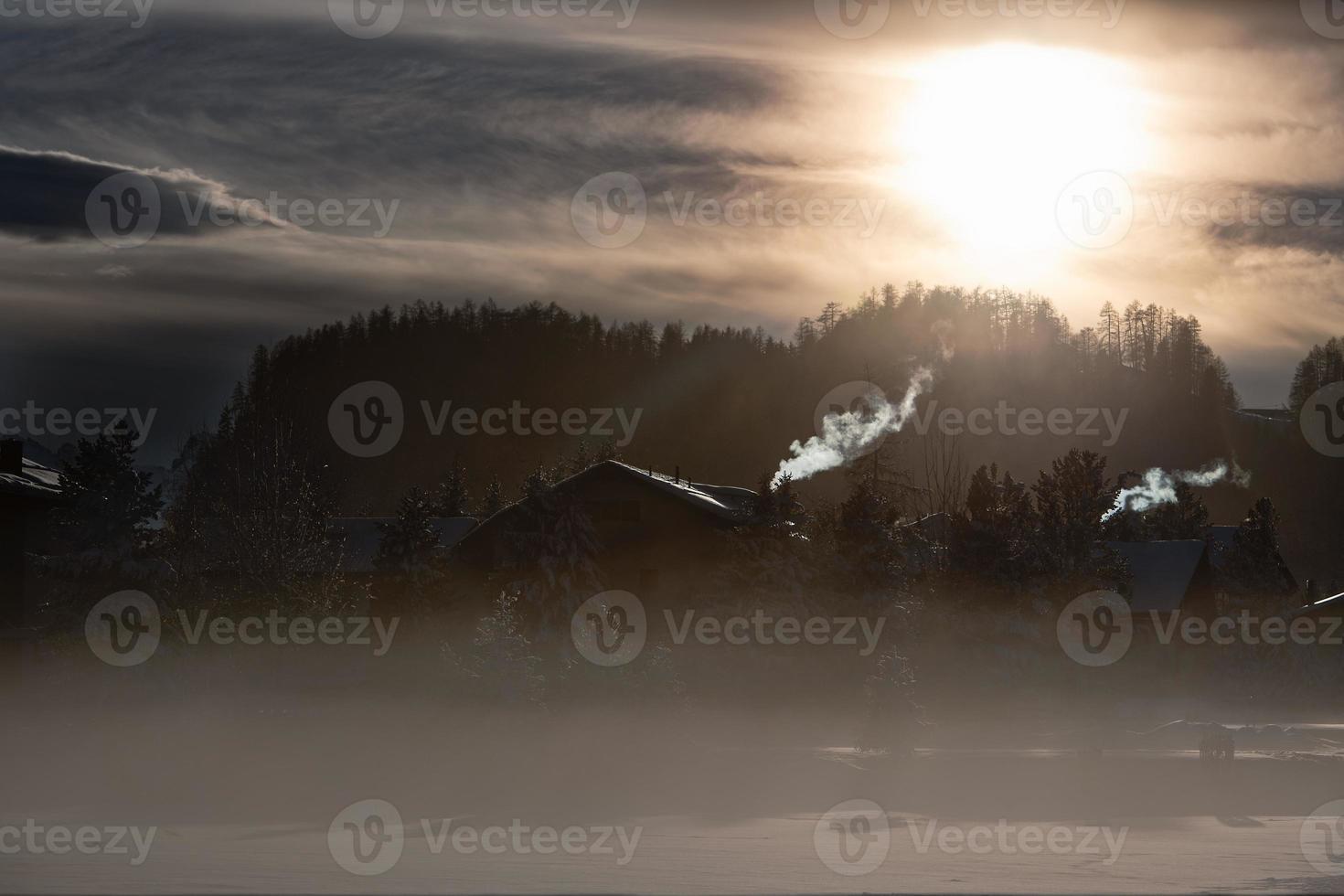 Humo de las chimeneas de un pueblo de montaña en el frío de la entrada al atardecer foto