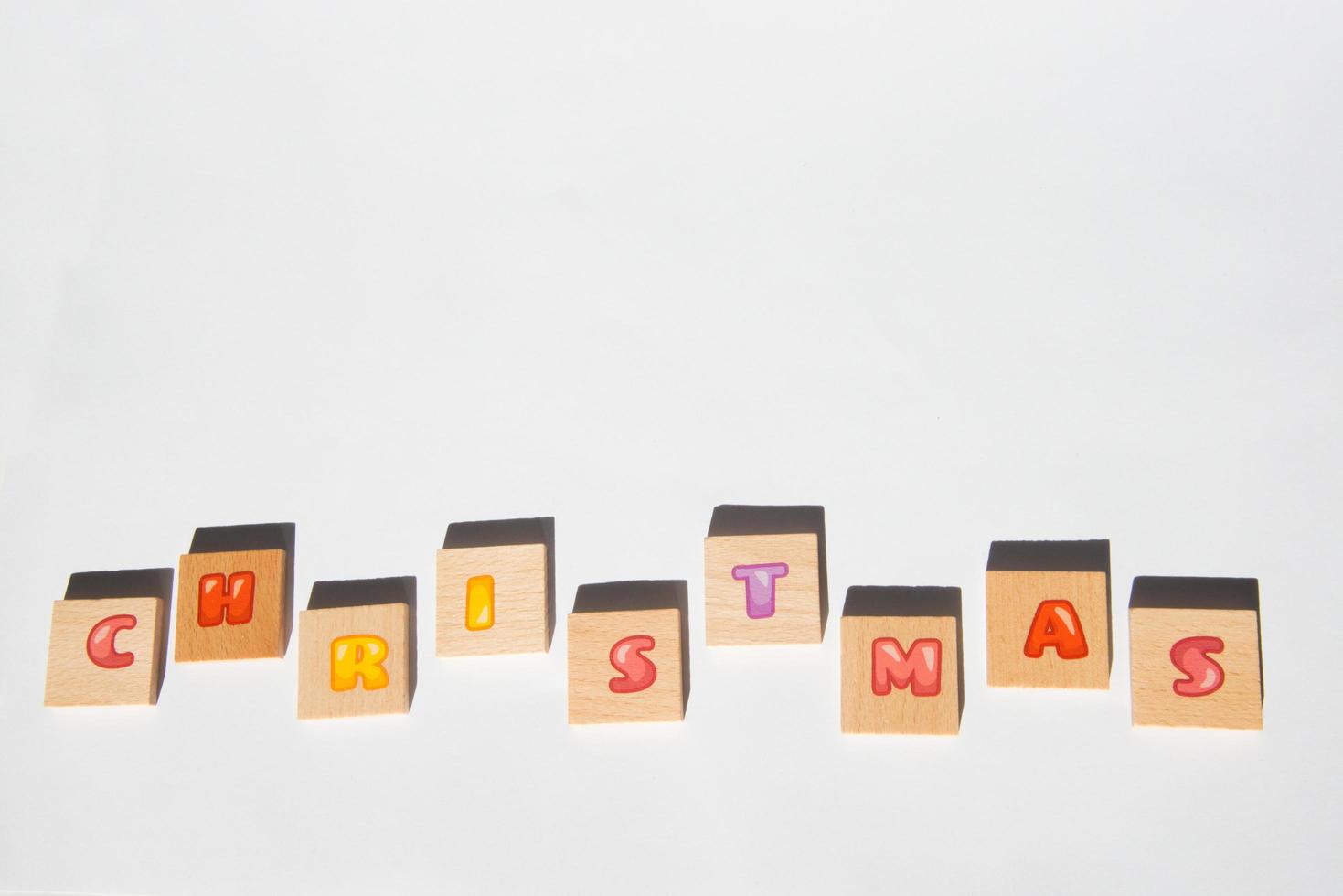 Word Christmas in wooden pieces with letters. Red color, white background photo