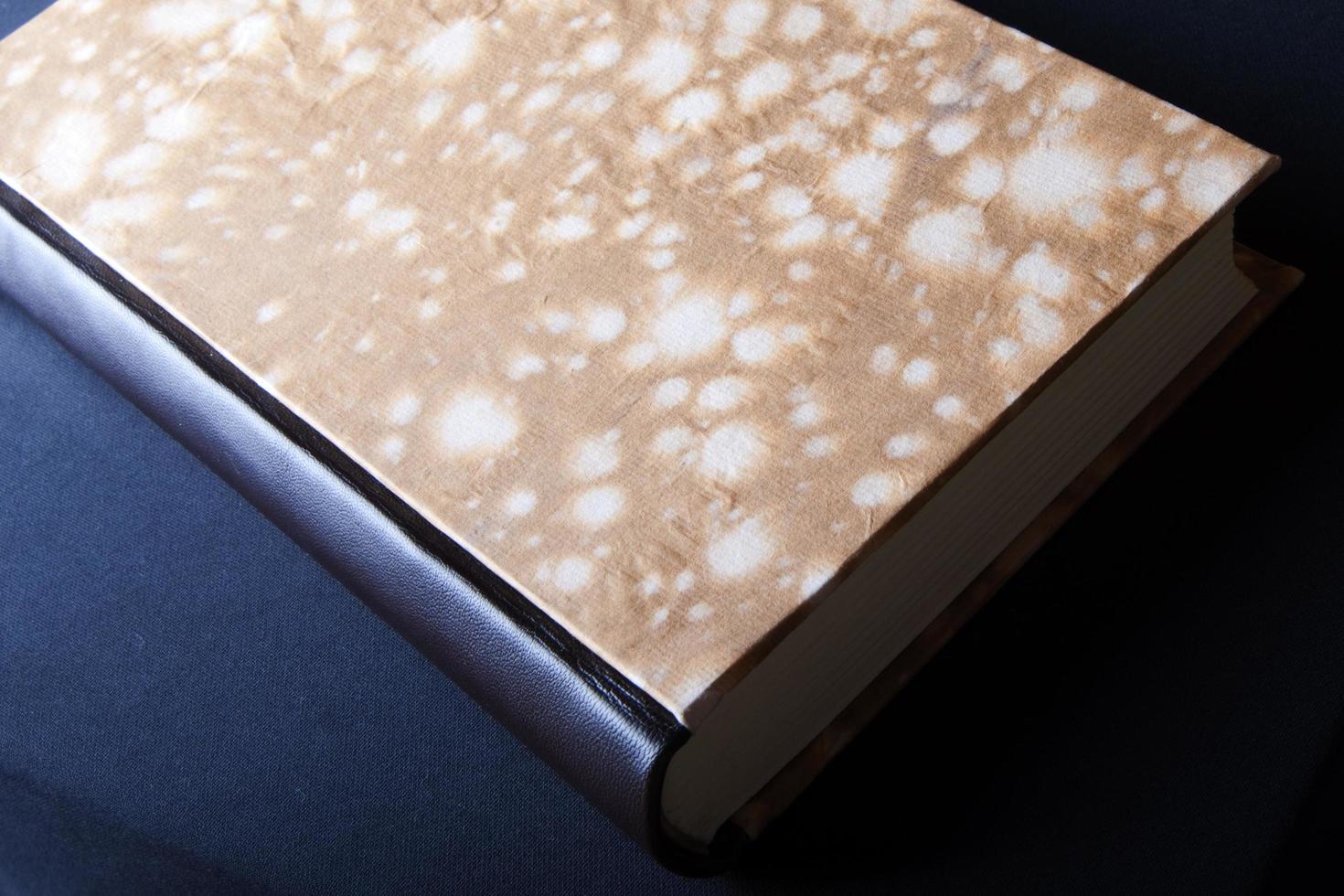 Art of Book binding. Handmade book with marble paper front and leather book spine seen from above photo