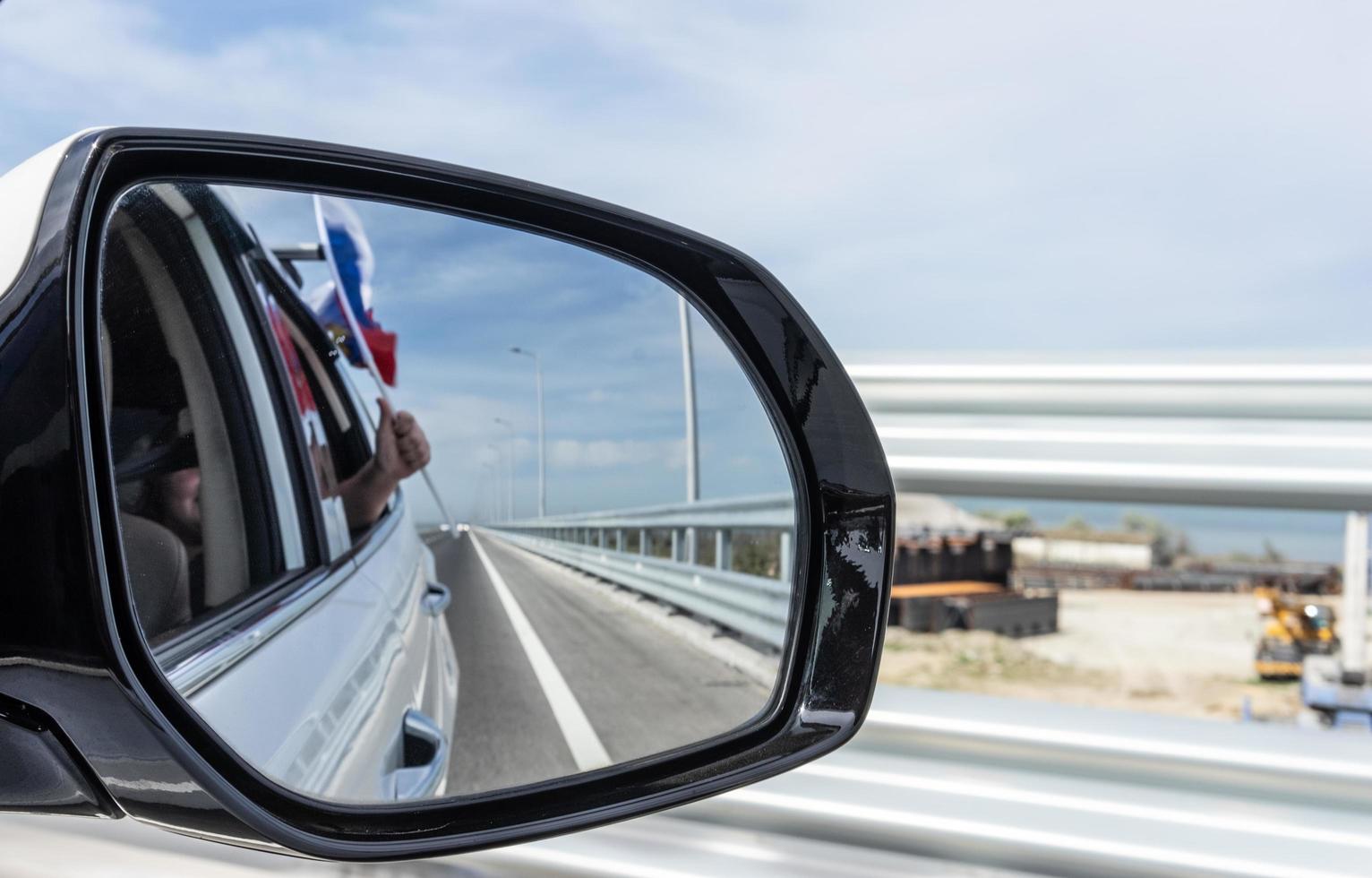 Car mirror with reflection of the road and the Russian flag photo