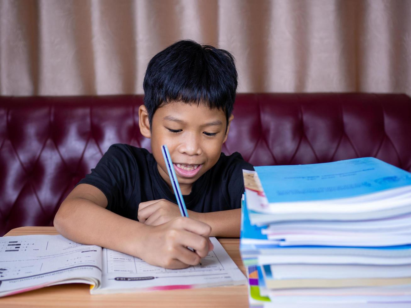 Boy doing homework and reading on a wooden table photo