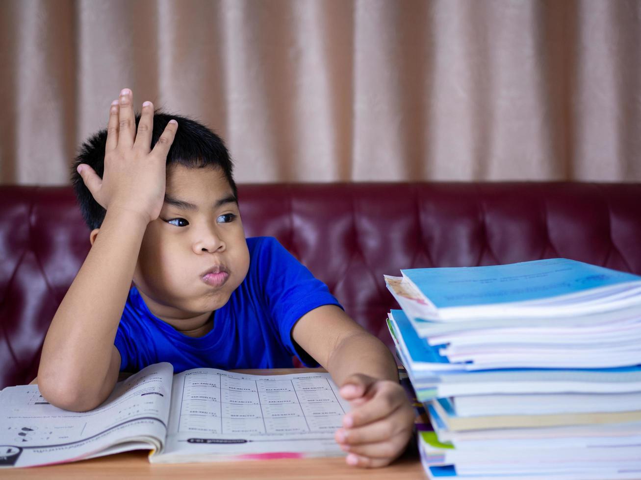 A boy is tired of reading a book on a wooden table photo