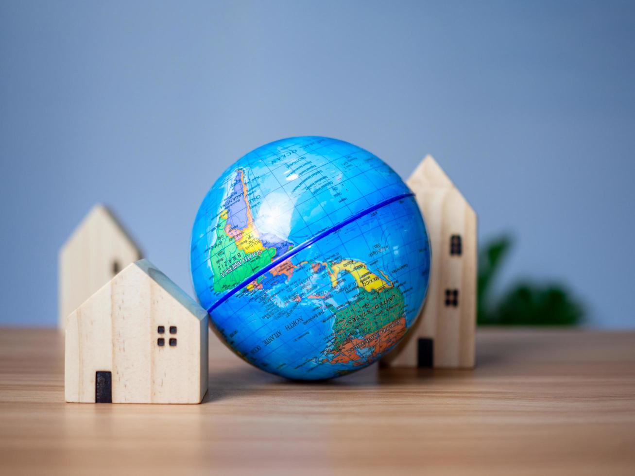 A wooden model house is placed beside a replica globe photo