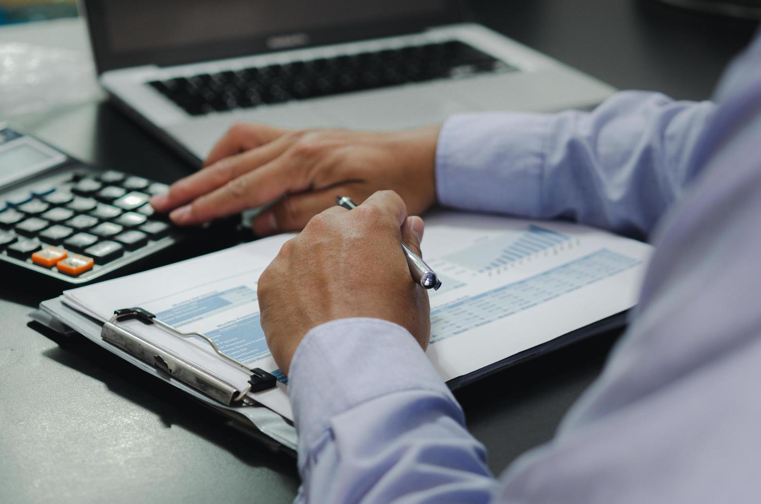 businessman hands holding pens and business documents at desk and calculator. Business, finance, tax and investment concept. photo