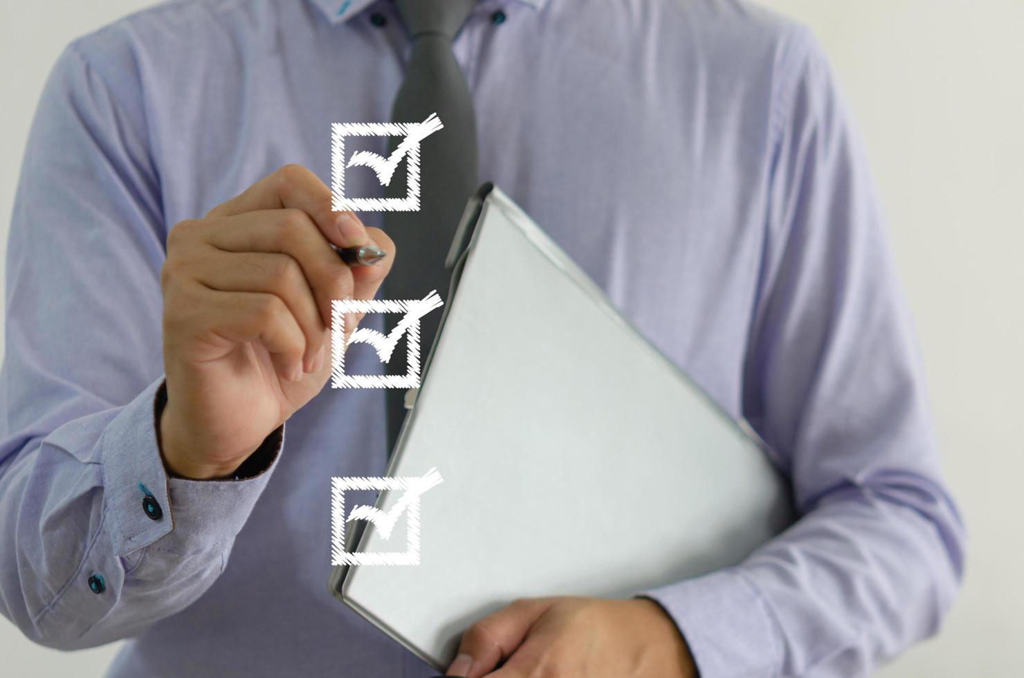 businessman holding a pen with a check mark on the square on a virtual screen photo