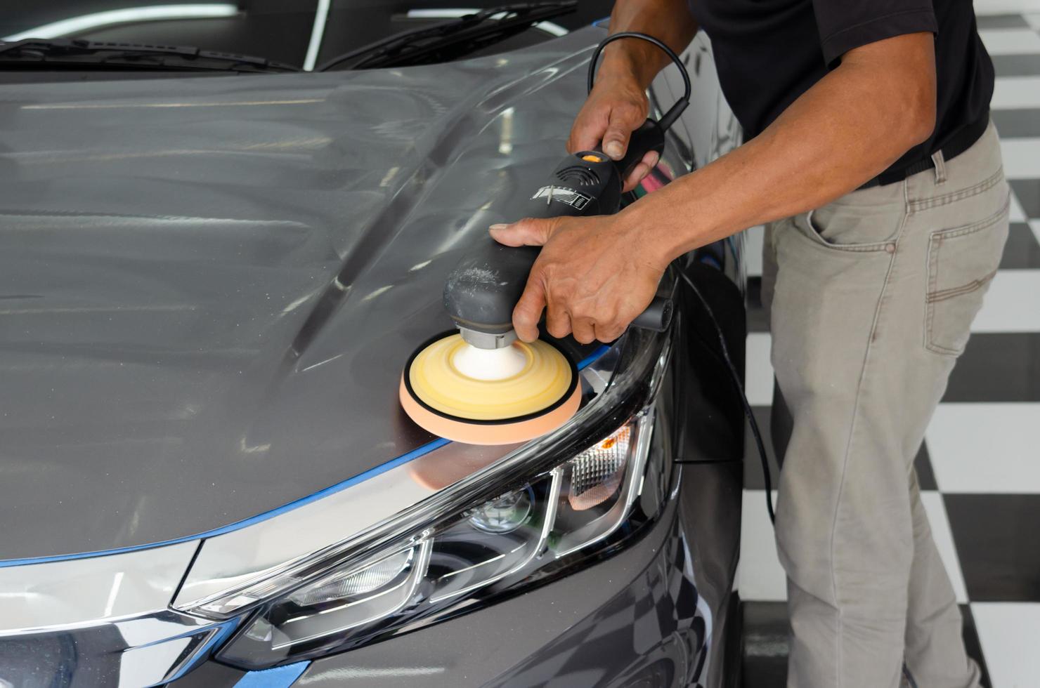 detalle del coche - mecánico masculino que sostiene la máquina pulidora del coche. industria automotriz, taller de pulido y pintura y reparación de automóviles. foto