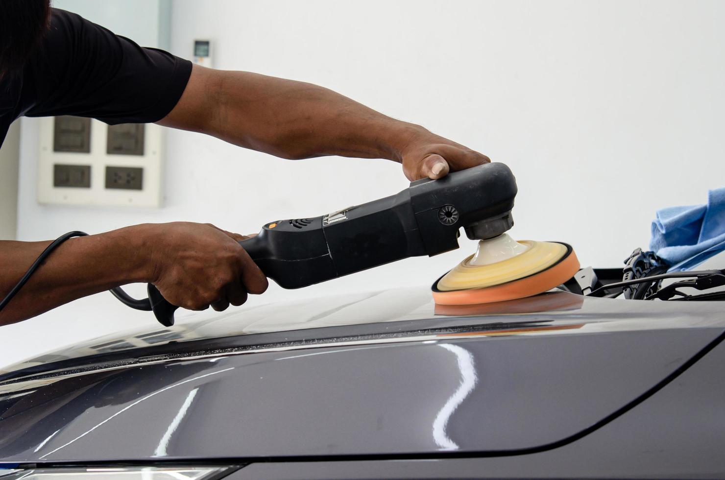 detalle del coche - mecánico masculino que sostiene la máquina pulidora del coche. industria automotriz, taller de pulido y pintura y reparación de automóviles. foto