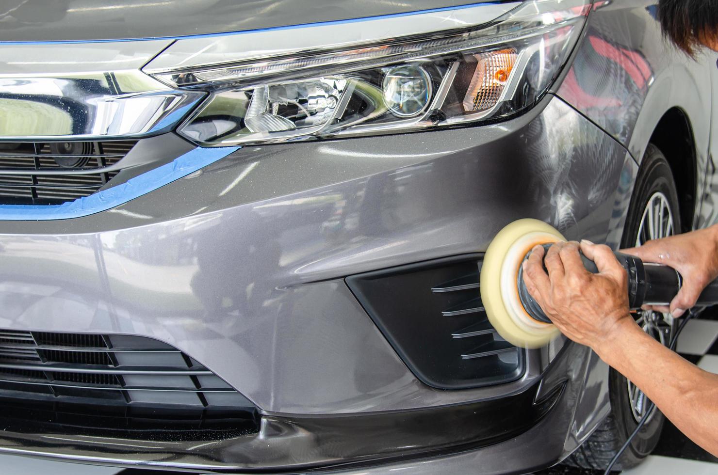 detalle del coche - mecánico masculino que sostiene la máquina pulidora del coche. industria automotriz, taller de pulido y pintura y reparación de automóviles. foto