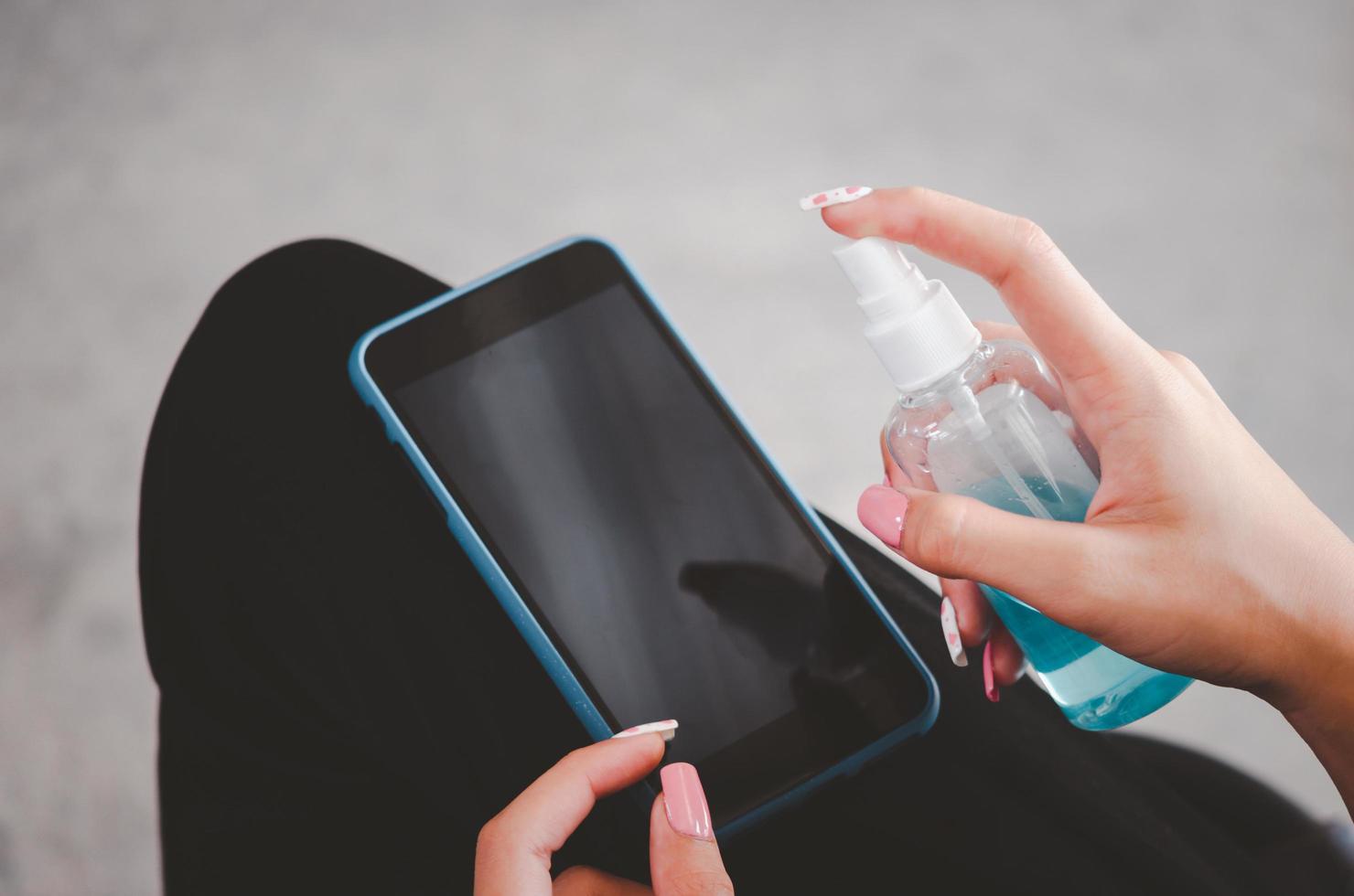 Spray to disinfect mobile phone with alcohol. concept of health care to prevent disease photo