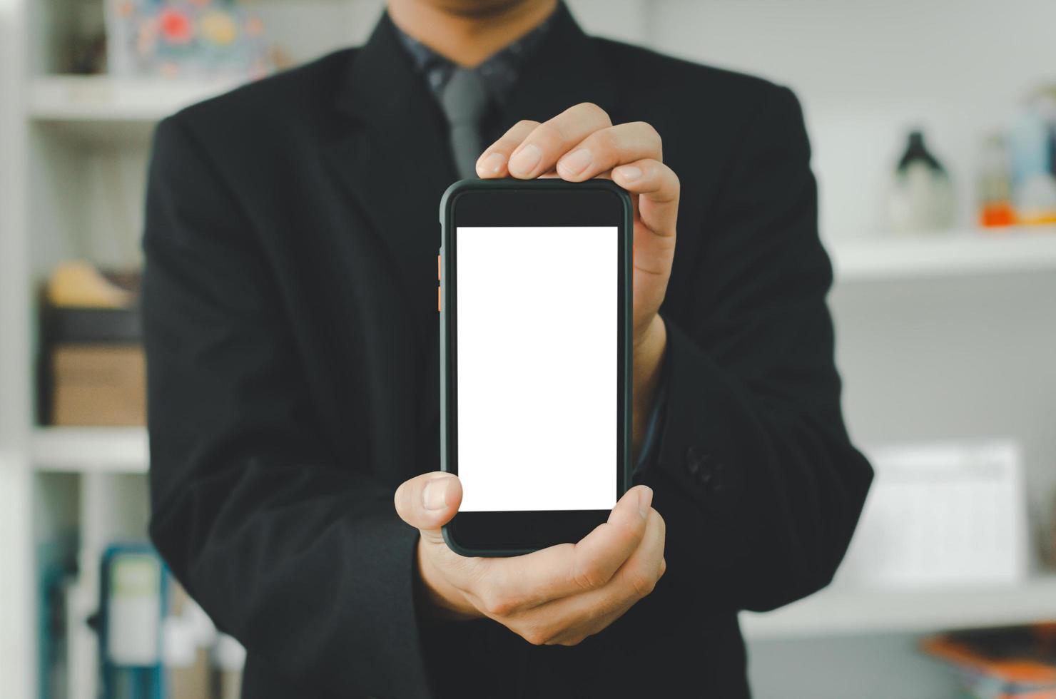 Businessman holding a blank white touch screen smartphone. Used to put text or information to advertise news or sell products online. concept marketing business photo