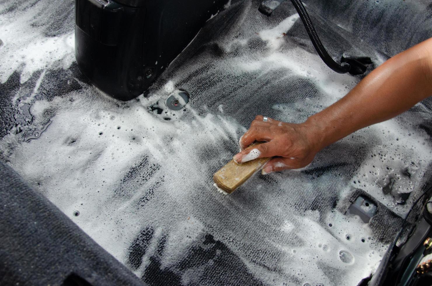 Wash the car carpet.Detailing on interior of modern car.Clean by using a brush and cleaning solution on the car carpet. photo