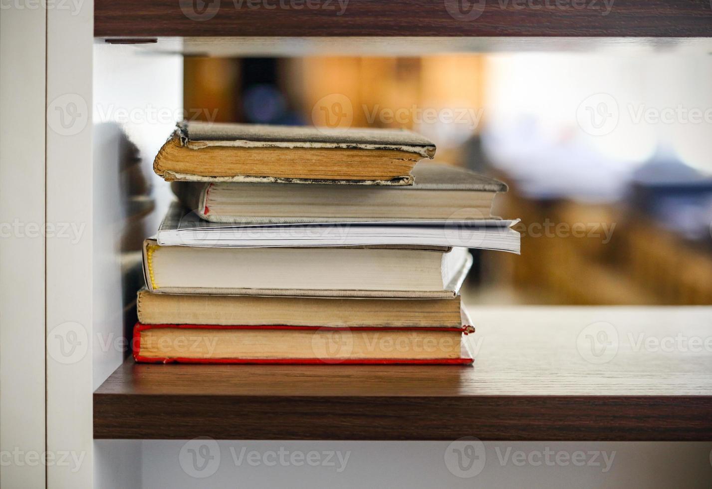 Many books stacked on black shelf with light bokeh photo