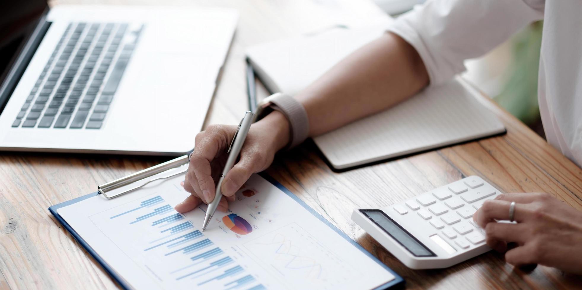 primer plano, una mujer de negocios trabaja en un informe de cuadro financiero, calcula los costos y las ganancias de la empresa y se sienta en su escritorio. foto