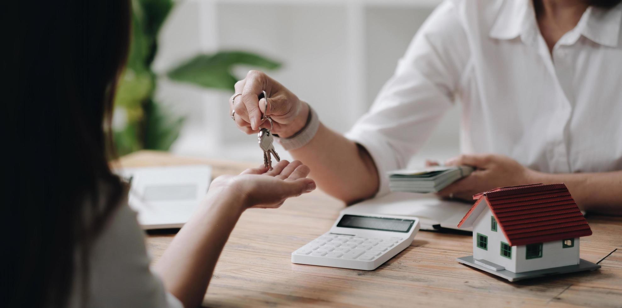 A new landlord receives a house keys chain from a real estate broker after paying a house deposit. Realtor and client, Real estate investment. photo